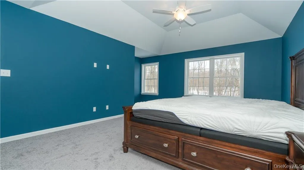 Bedroom with light carpet, a ceiling fan, and lofted ceiling Bedroom with light carpet, a ceiling fan, and lofted ceiling