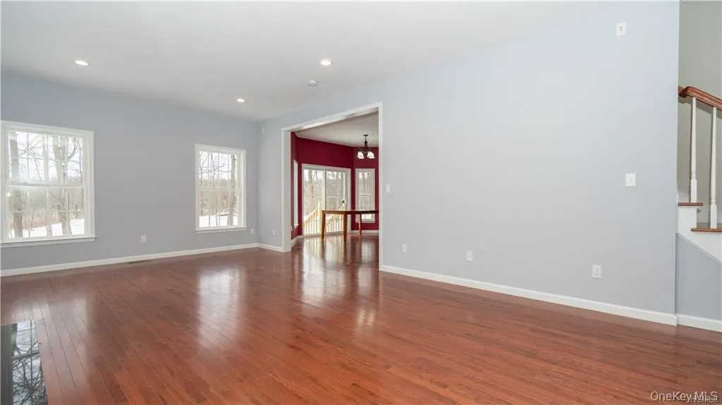 Empty room with dark wood-type flooring, a chandelier, recessed lighting, and stairway Empty room with dark wood-type flooring, a chandelier, recessed lighting, and stairway