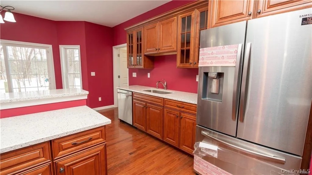 Kitchen with stainless steel appliances, glass insert cabinets, brown cabinets, and light stone counters Kitchen with stainless steel appliances, glass insert cabinets, brown cabinets, and light stone counters