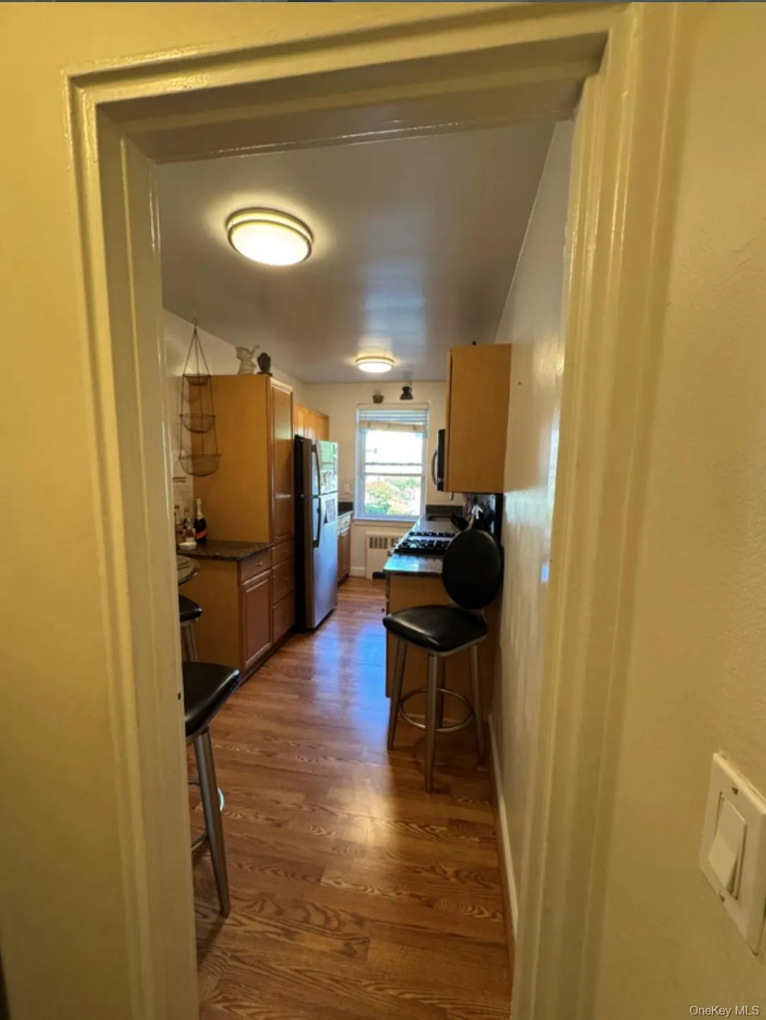 Kitchen with dark wood-type flooring, freestanding refrigerator, a breakfast bar area, and radiator Kitchen with dark wood-type flooring, freestanding refrigerator, a breakfast bar area, and radiator