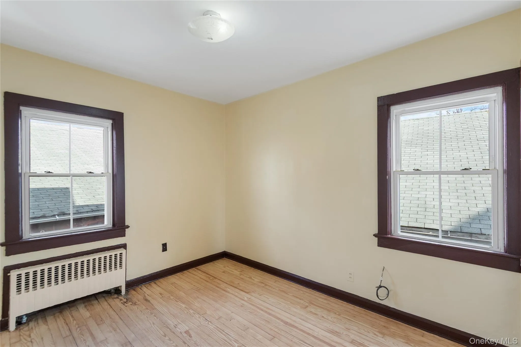 Unfurnished room featuring radiator and light wood-type flooring Unfurnished room featuring radiator and light wood-type flooring
