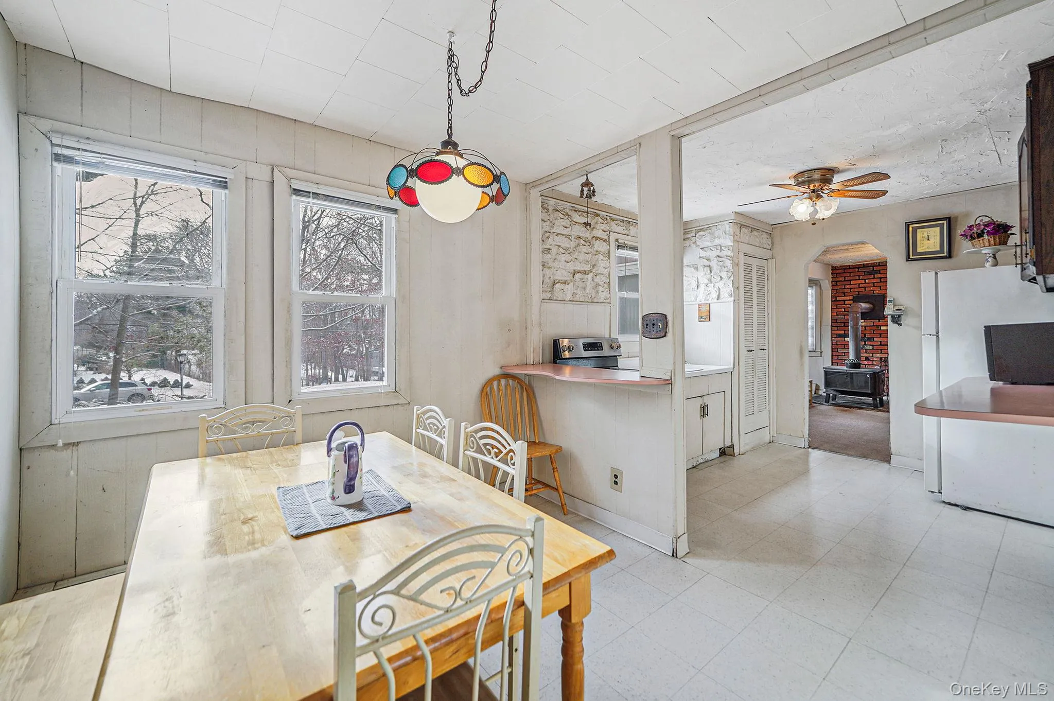 Dining space with a wood stove, ceiling fan, light flooring, and arched walkways Dining space with a wood stove, ceiling fan, light flooring, and arched walkways