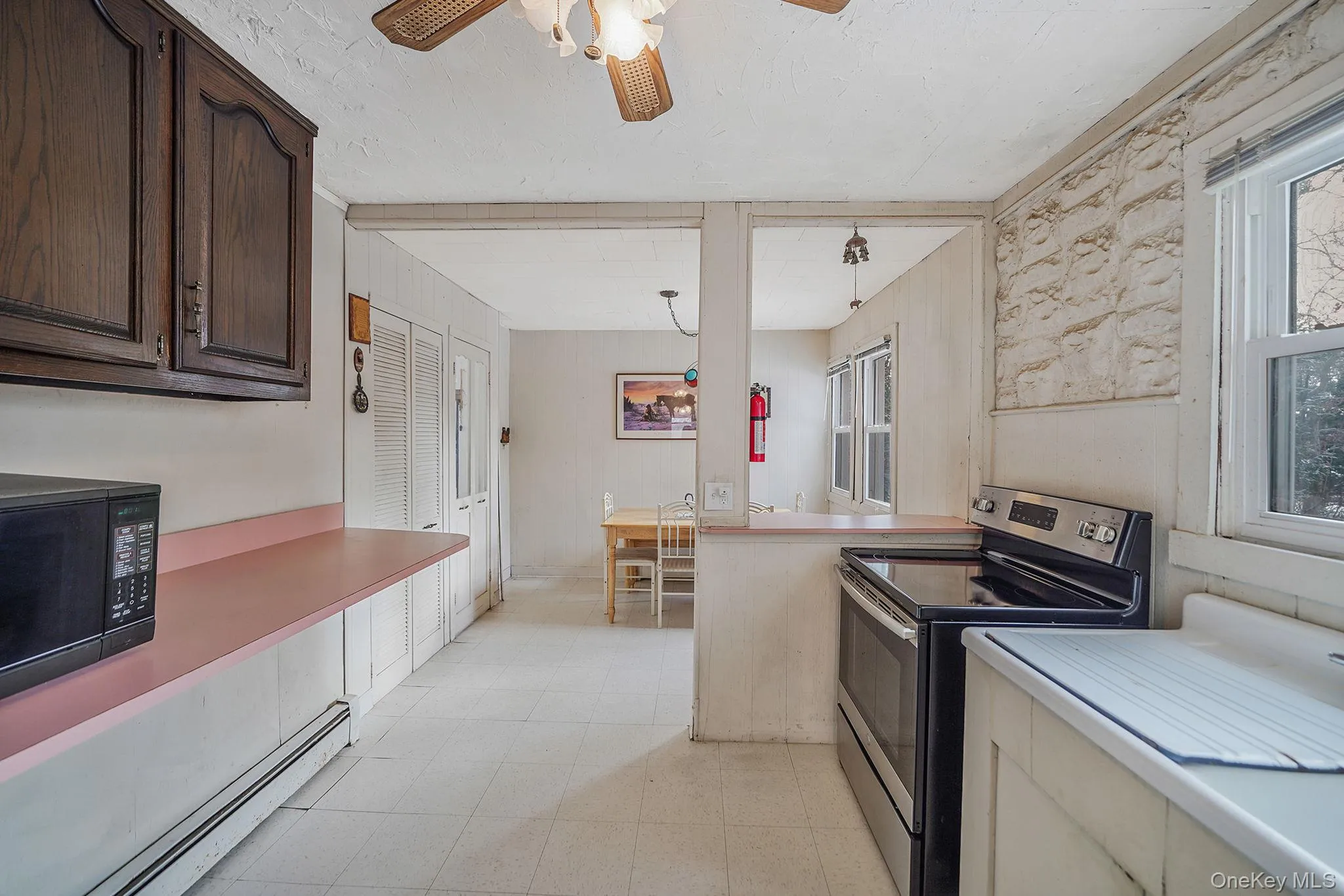Kitchen featuring stainless steel electric range, a baseboard radiator, light countertops, light flooring, and black microwave Kitchen featuring stainless steel electric range, a baseboard radiator, light countertops, light flooring, and black microwave
