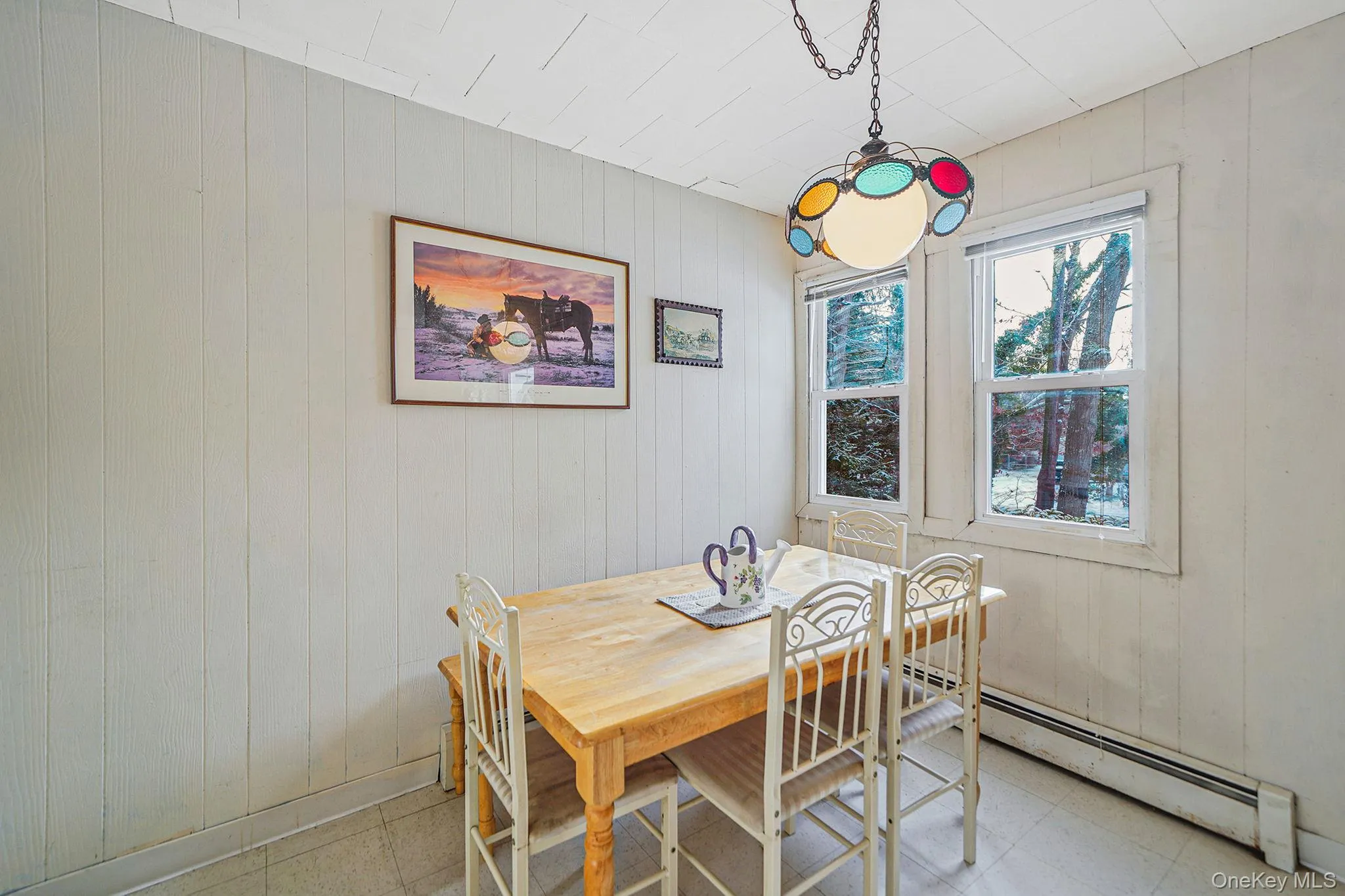 Dining space featuring wooden walls, tile patterned floors, and a baseboard heating unit Dining space featuring wooden walls, tile patterned floors, and a baseboard heating unit