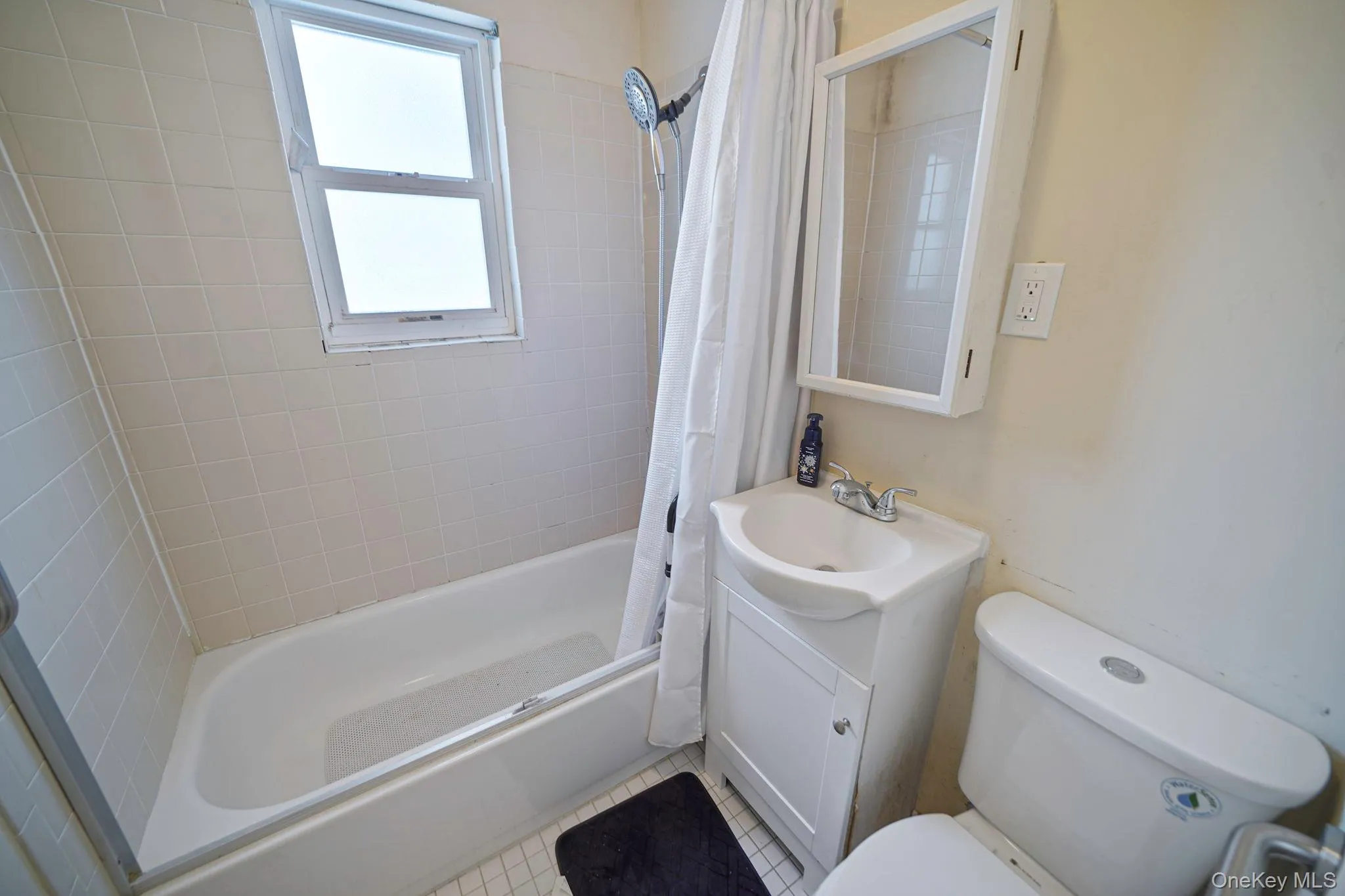 Full bathroom with vanity, shower / bathtub combination with curtain, and tile patterned floors Full bathroom with vanity, shower / bathtub combination with curtain, and tile patterned floors