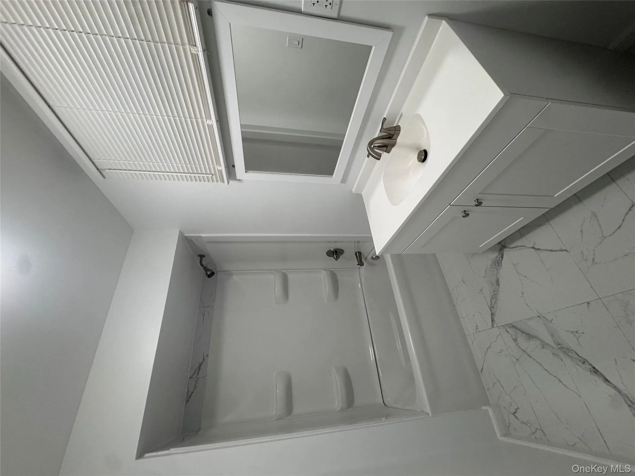 Bathroom with light marble finish flooring, vanity, and shower combination Bathroom with light marble finish flooring, vanity, and shower combination