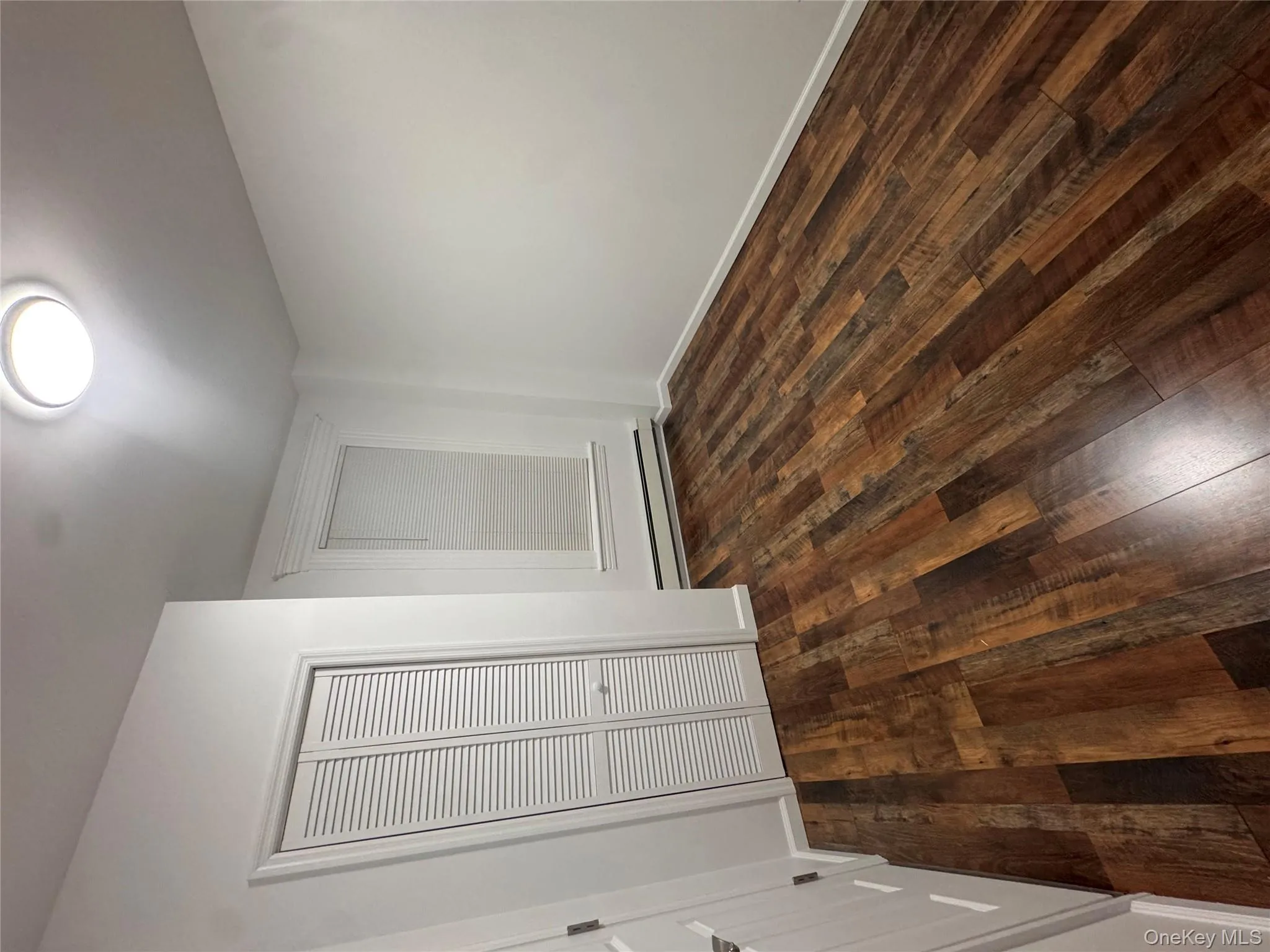Unfurnished bedroom featuring dark wood-type flooring, a closet, and a baseboard heating unit Unfurnished bedroom featuring dark wood-type flooring, a closet, and a baseboard heating unit