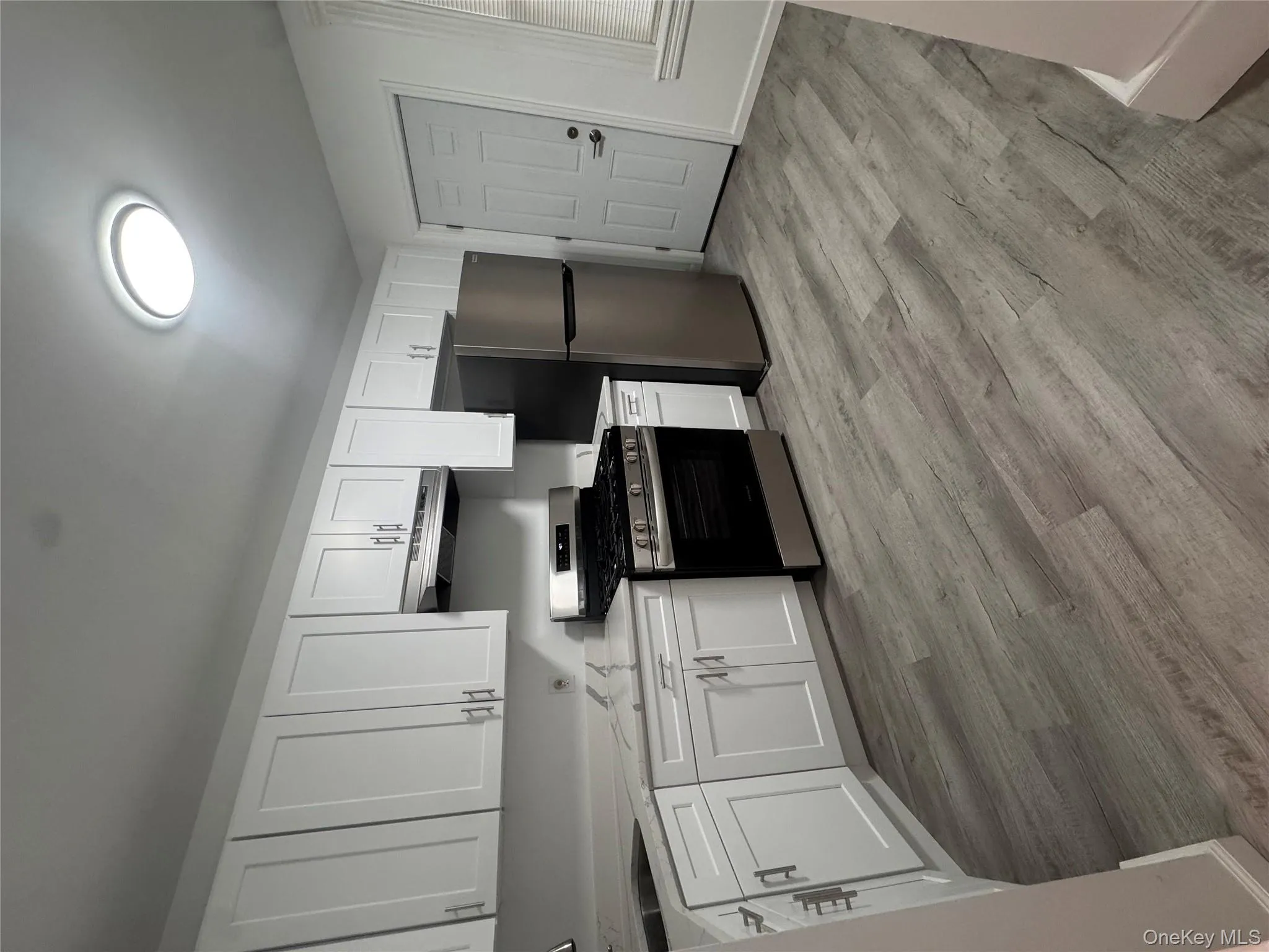 Kitchen featuring stainless steel gas range, white cabinets, refrigerator, and exhaust hood Kitchen featuring stainless steel gas range, white cabinets, refrigerator, and exhaust hood