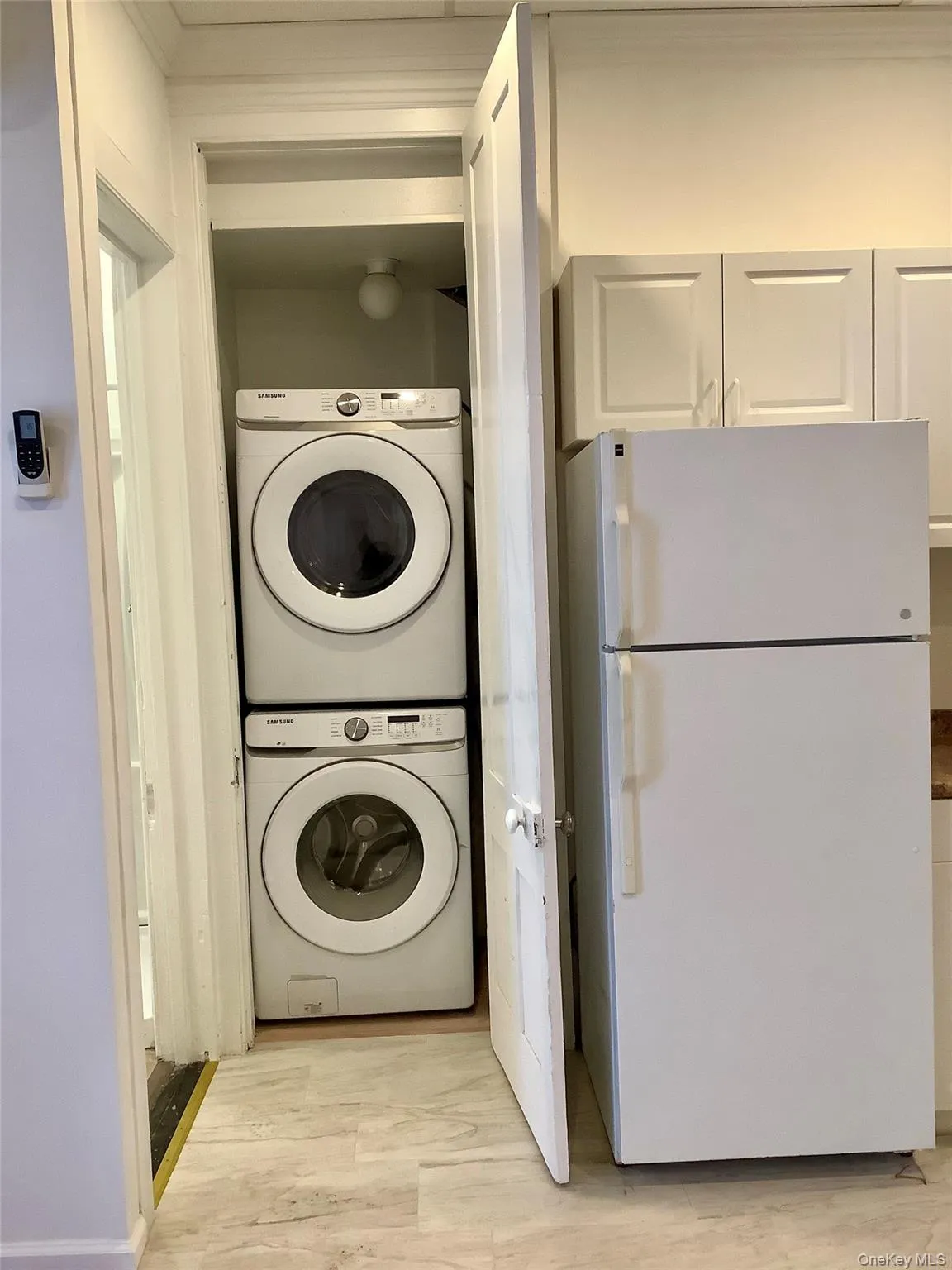 Laundry room with estacked washer and dryer and light wood-style flooring Laundry room with estacked washer and dryer and light wood-style flooring