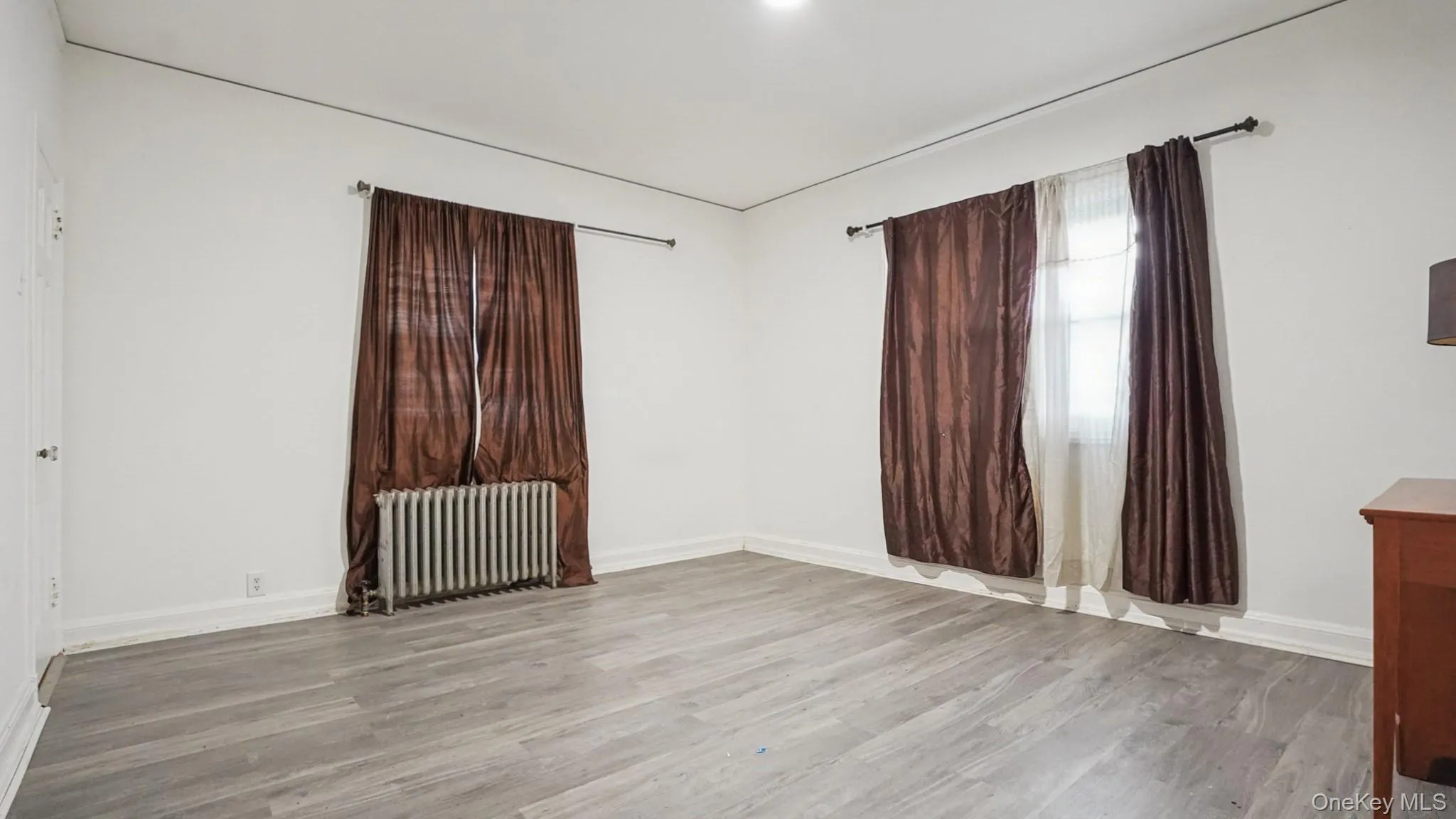 Unfurnished room featuring radiator and light wood-type flooring Unfurnished room featuring radiator and light wood-type flooring