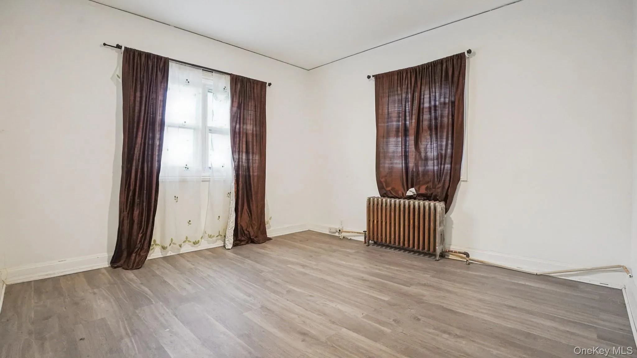 Unfurnished room with radiator heating unit and wood finished floors Unfurnished room with radiator heating unit and wood finished floors