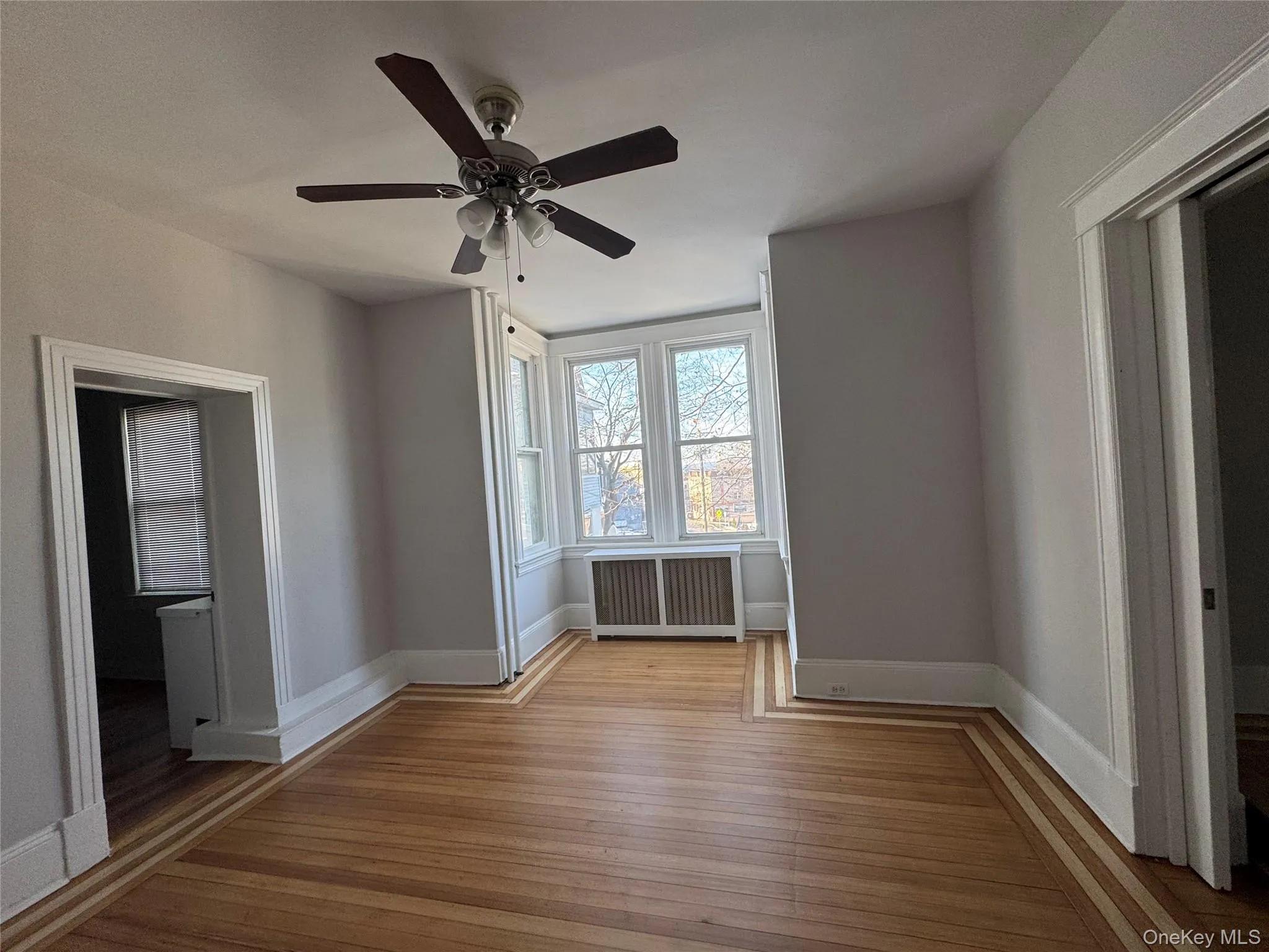 Spare room with radiator heating unit, light wood-style flooring, and ceiling fan Spare room with radiator heating unit, light wood-style flooring, and ceiling fan