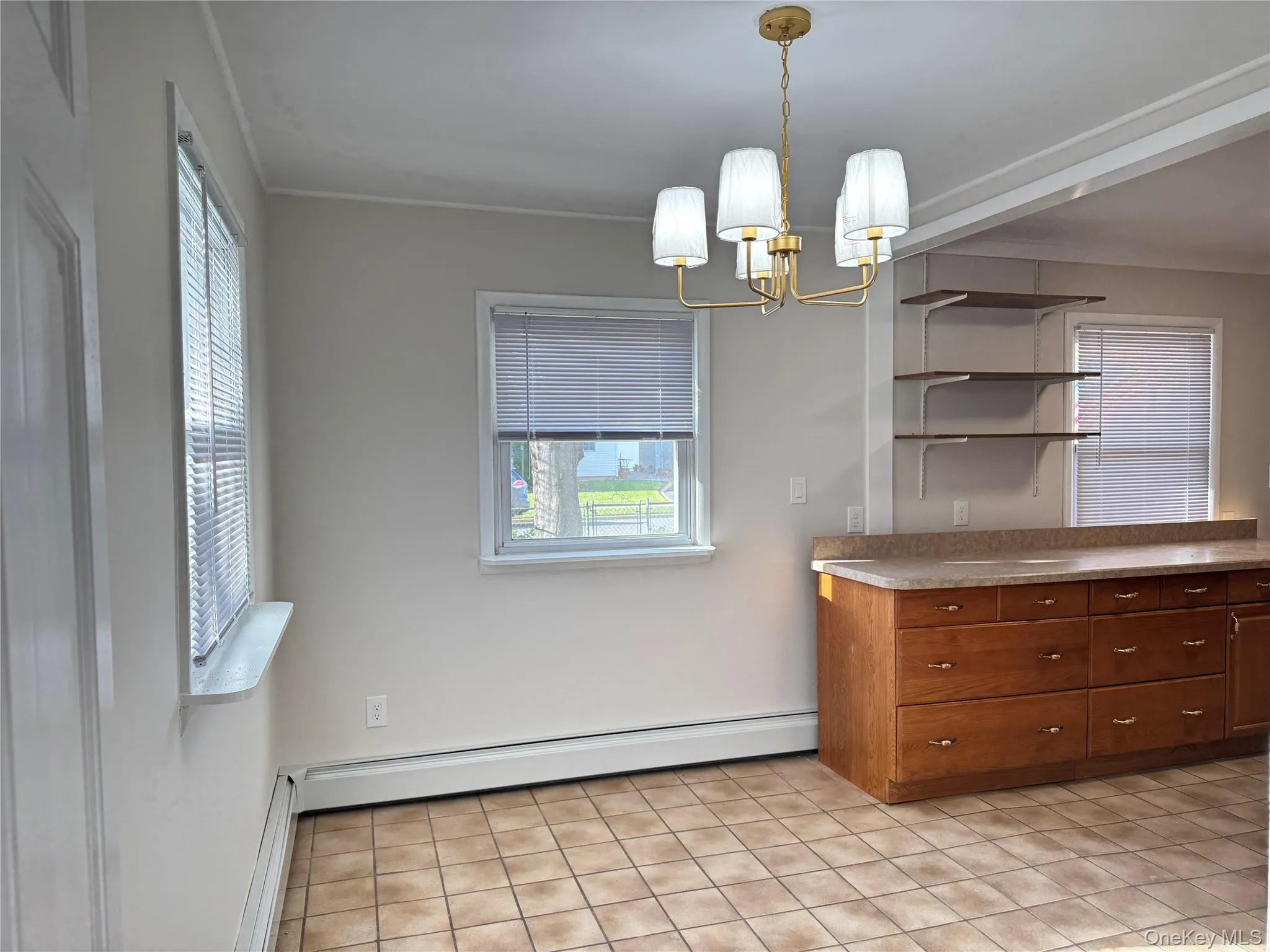 Dining space featuring a baseboard radiator, light tile patterned flooring, a chandelier, and ornamental molding Dining space featuring a baseboard radiator, light tile patterned flooring, a chandelier, and ornamental molding