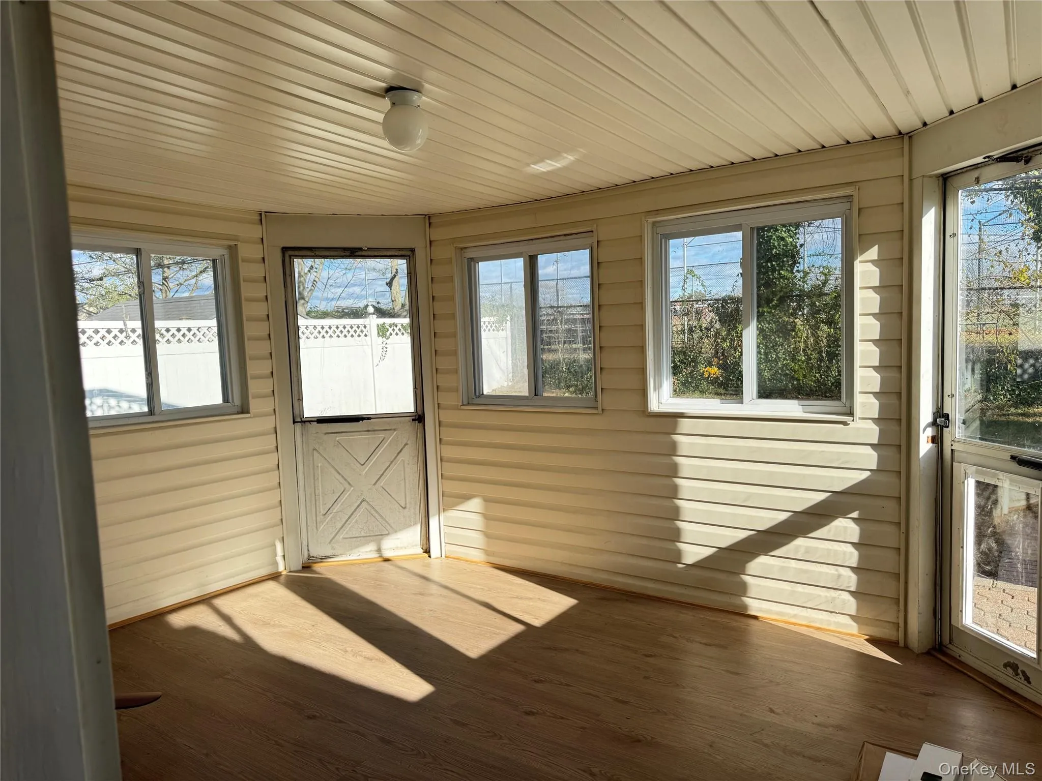 Unfurnished sunroom with healthy amount of natural light, wood finished floors, wood ceiling, and wood walls Unfurnished sunroom with healthy amount of natural light, wood finished floors, wood ceiling, and wood walls