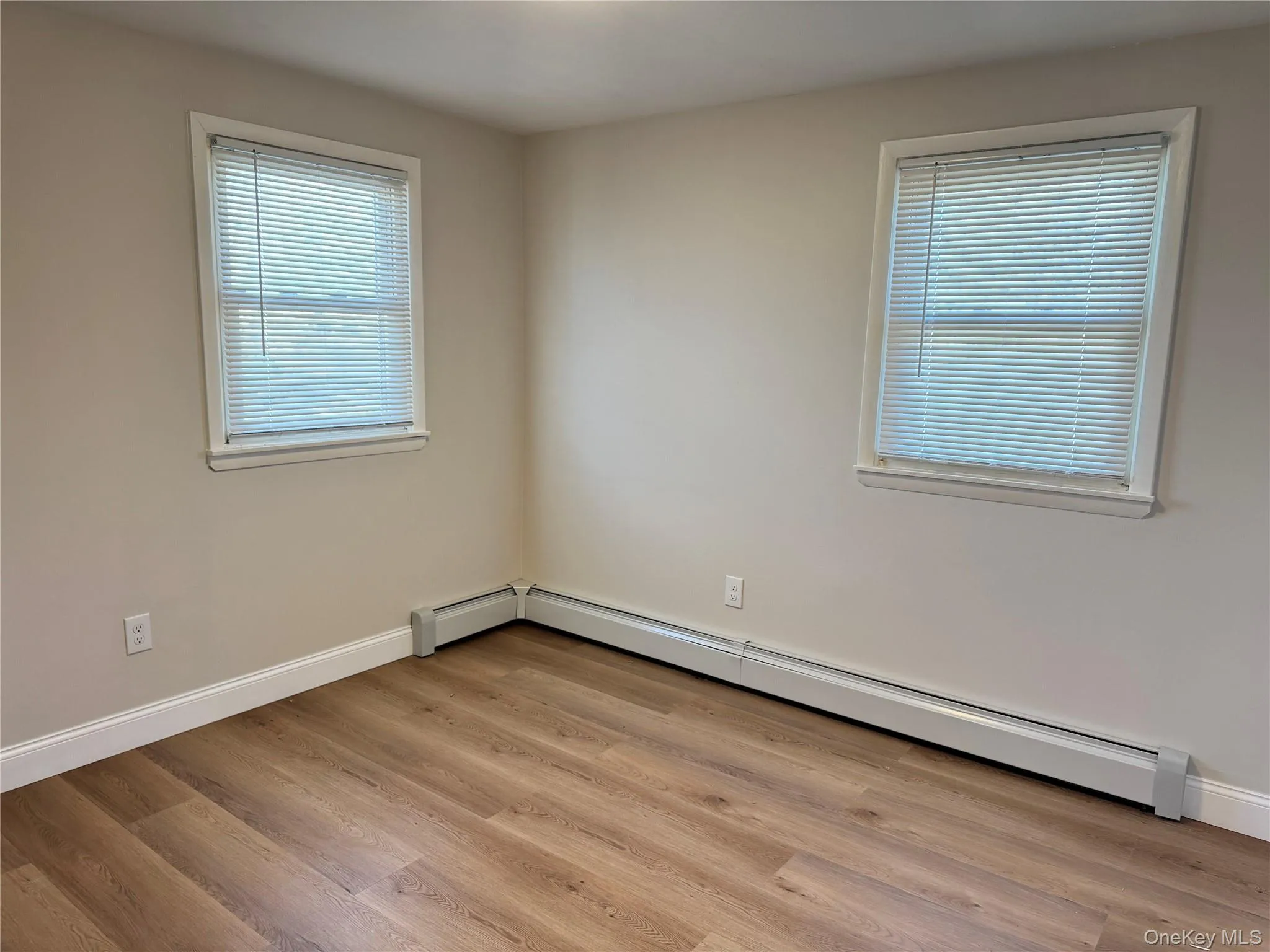 Unfurnished room with a baseboard heating unit and light wood-style flooring Unfurnished room with a baseboard heating unit and light wood-style flooring