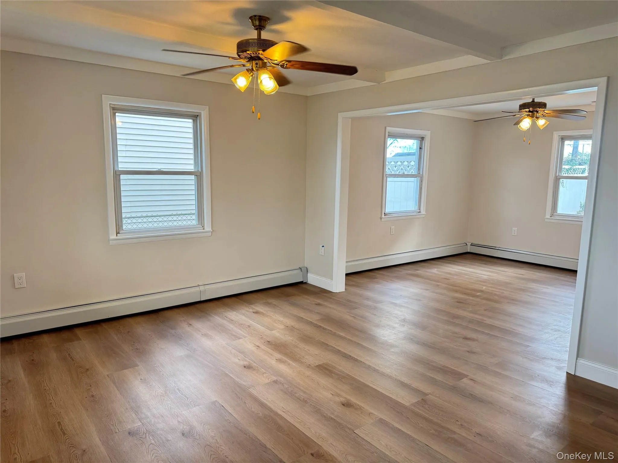 Unfurnished room featuring baseboard heating, a ceiling fan, light wood finished floors, and beam ceiling Unfurnished room featuring baseboard heating, a ceiling fan, light wood finished floors, and beam ceiling
