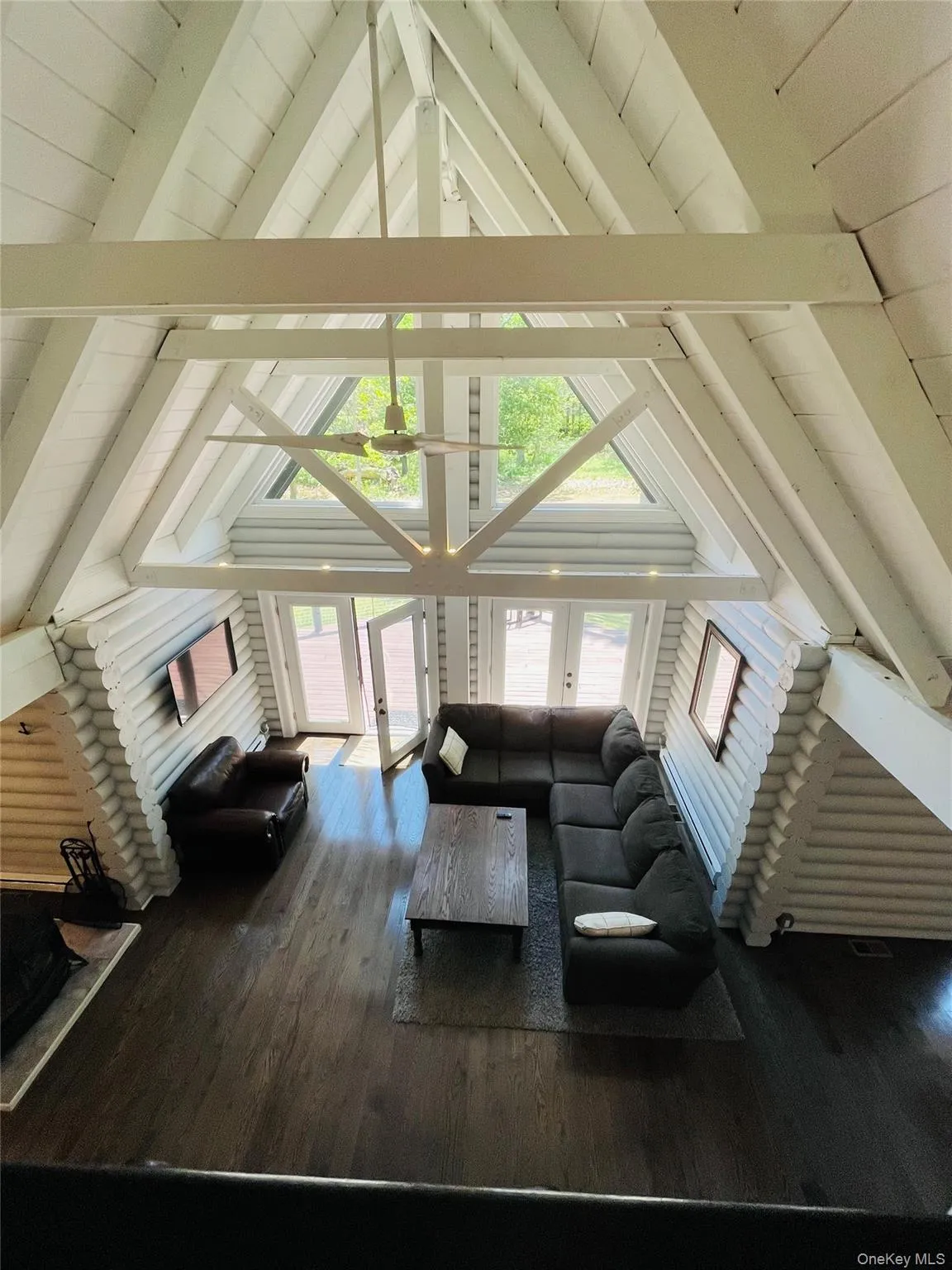 Living area featuring dark wood-style flooring, high vaulted ceiling, and a wooden ceiling with exposed beams Living area featuring dark wood-style flooring, high vaulted ceiling, and a wooden ceiling with exposed beams