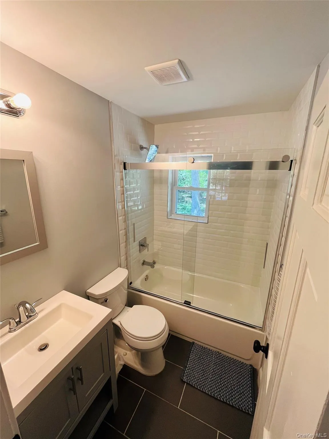 Full bath with vanity, dark tile patterned flooring, and enclosed tub / shower combo Full bath with vanity, dark tile patterned flooring, and enclosed tub / shower combo
