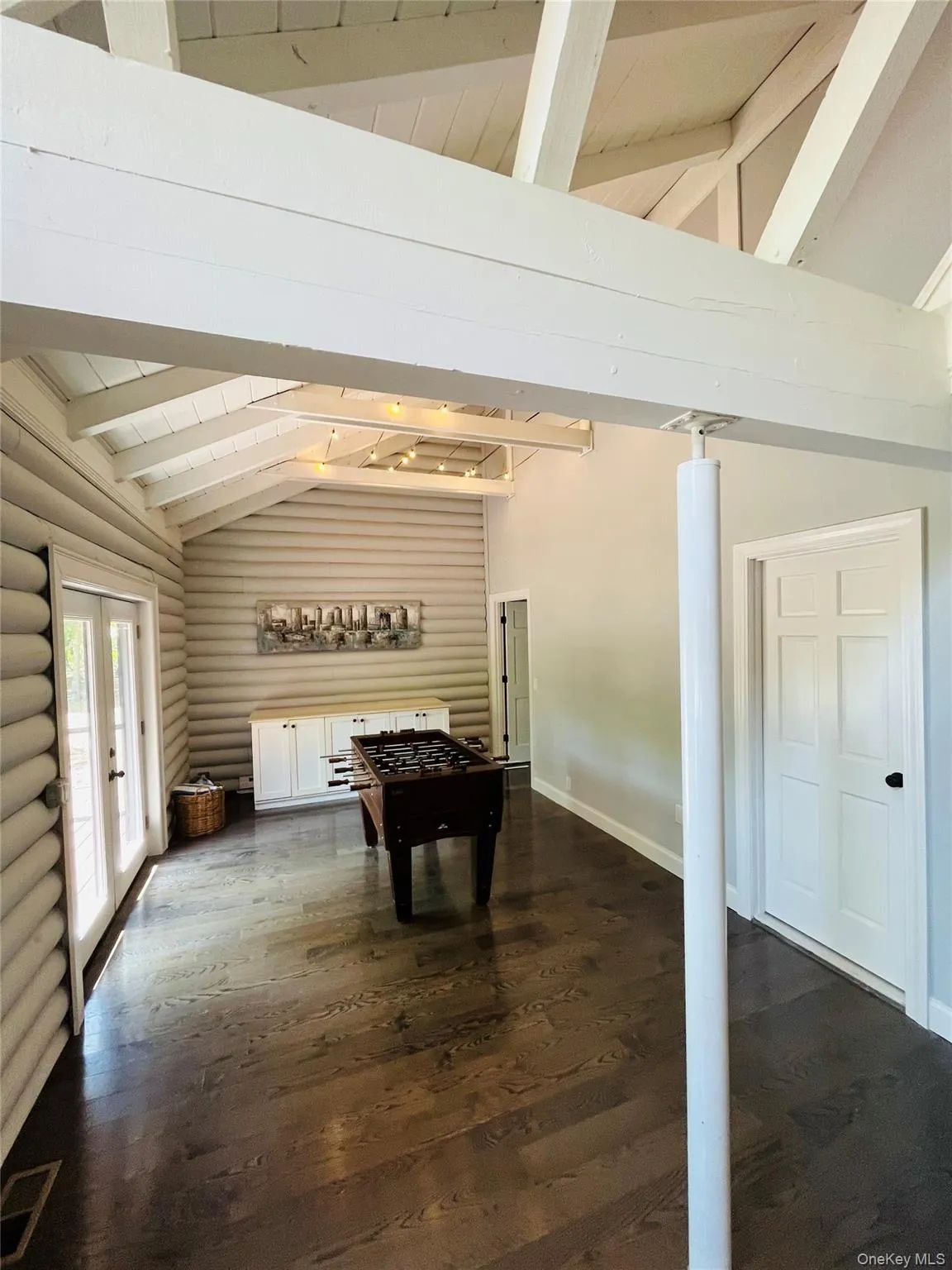 Game room featuring french doors, dark wood-style flooring, rustic walls, and wooden ceiling Game room featuring french doors, dark wood-style flooring, rustic walls, and wooden ceiling
