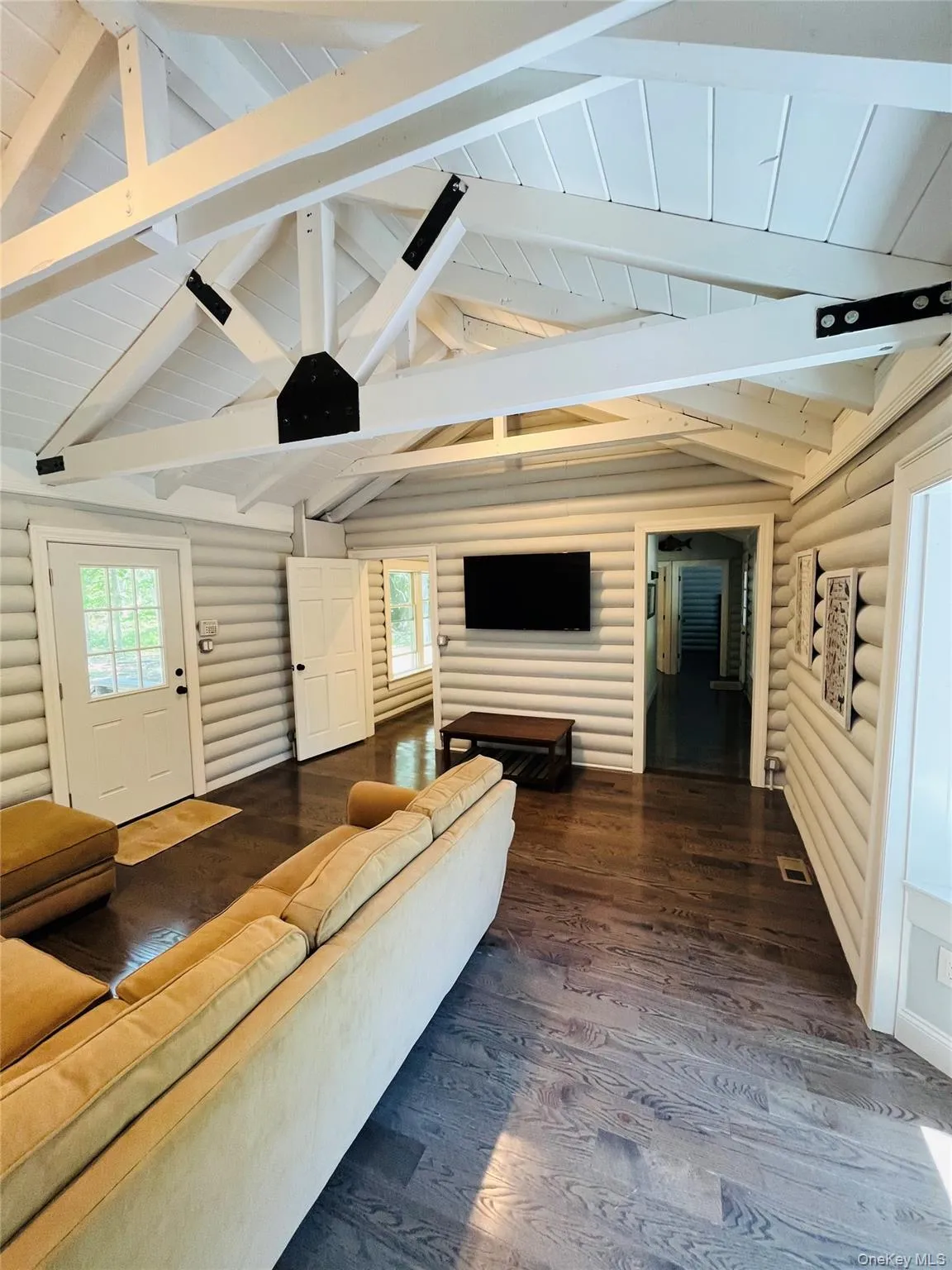 Living area featuring dark wood finished floors, log walls, and wooden ceiling Living area featuring dark wood finished floors, log walls, and wooden ceiling