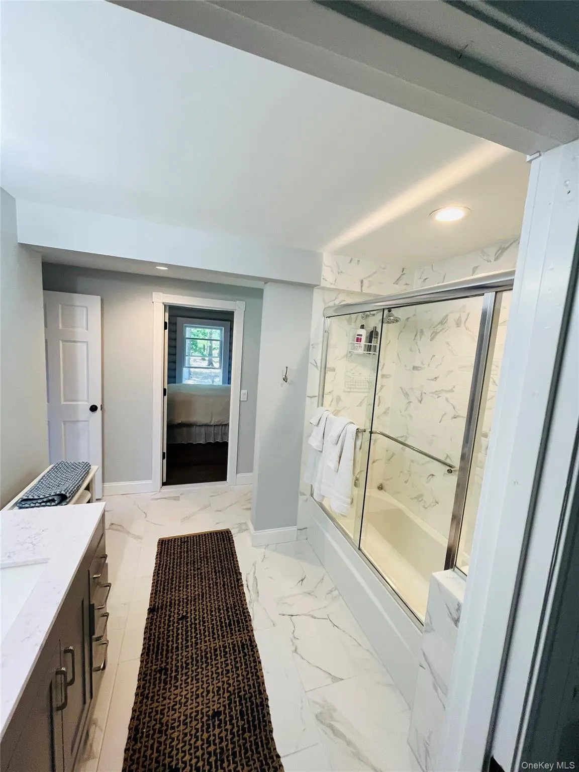 Full bath featuring vanity, light marble finish flooring, shower / bath combination with glass door, and recessed lighting Full bath featuring vanity, light marble finish flooring, shower / bath combination with glass door, and recessed lighting