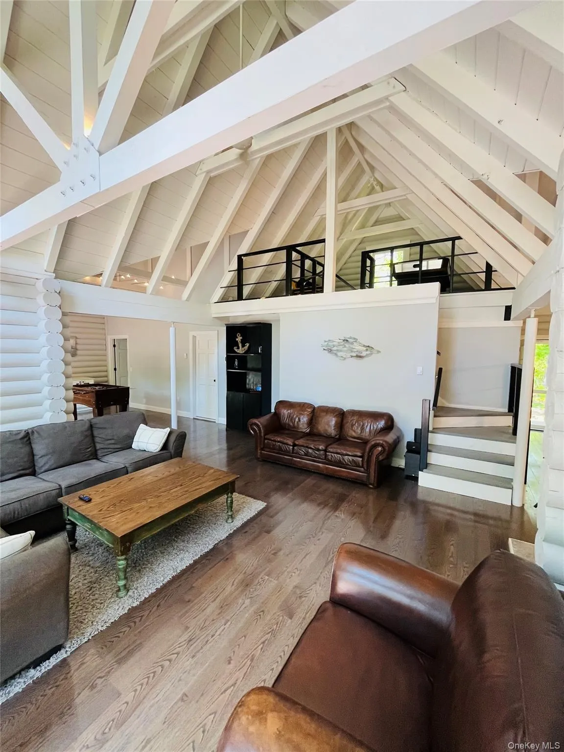 Living area featuring high vaulted ceiling, beam ceiling, and wood finished floors Living area featuring high vaulted ceiling, beam ceiling, and wood finished floors