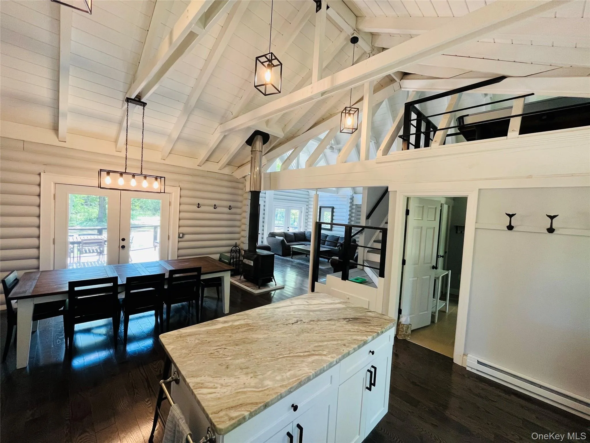 Kitchen featuring hanging light fixtures, high vaulted ceiling, a wood stove, a baseboard heating unit, and dark wood-type flooring Kitchen featuring hanging light fixtures, high vaulted ceiling, a wood stove, a baseboard heating unit, and dark wood-type flooring