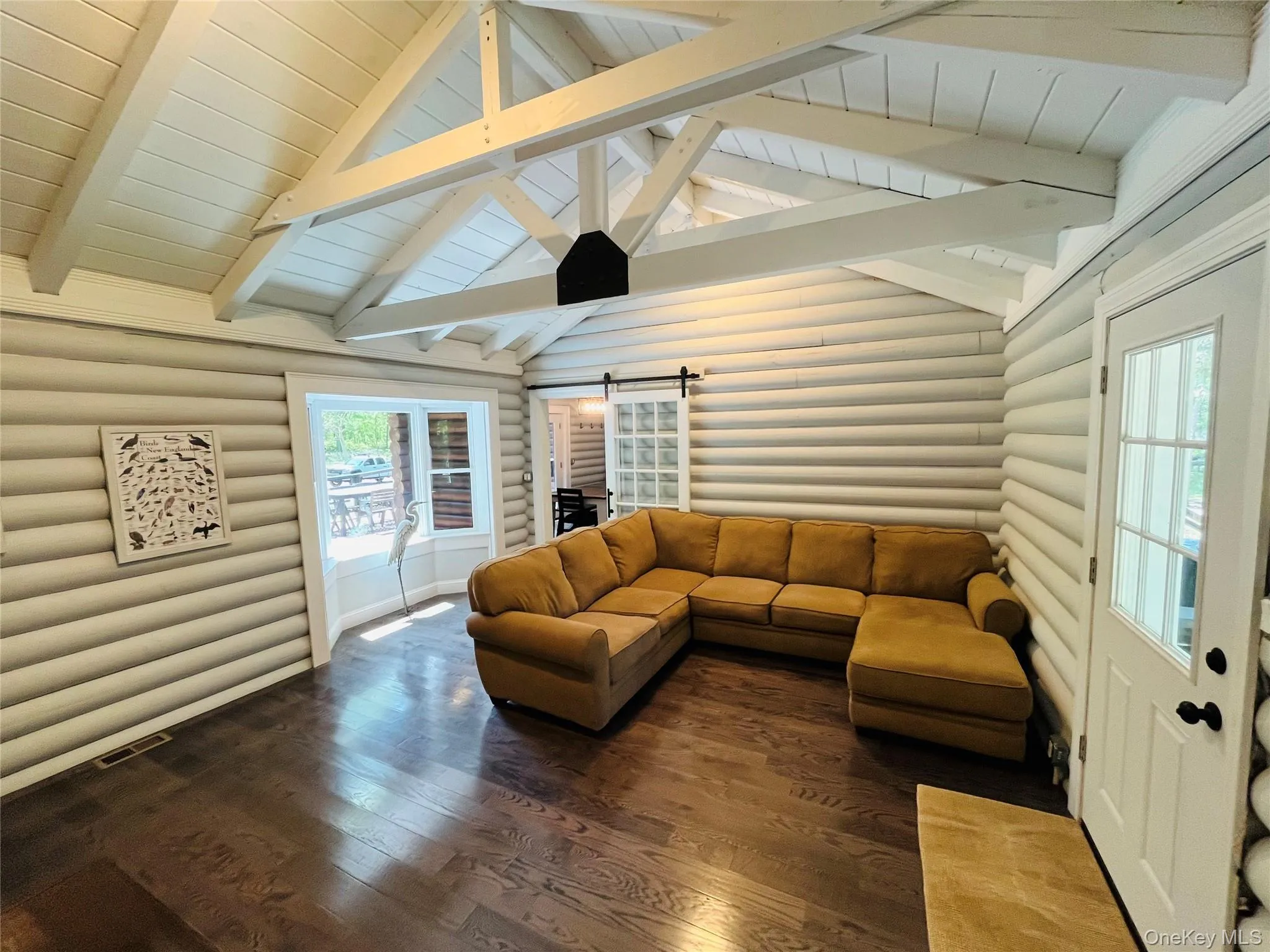 Living area featuring a barn door, log walls, hardwood / wood-style floors, and wooden ceiling Living area featuring a barn door, log walls, hardwood / wood-style floors, and wooden ceiling