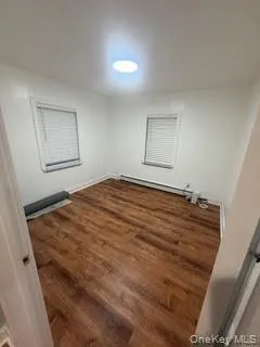 Spare room with dark wood-style flooring and a baseboard radiator Spare room with dark wood-style flooring and a baseboard radiator