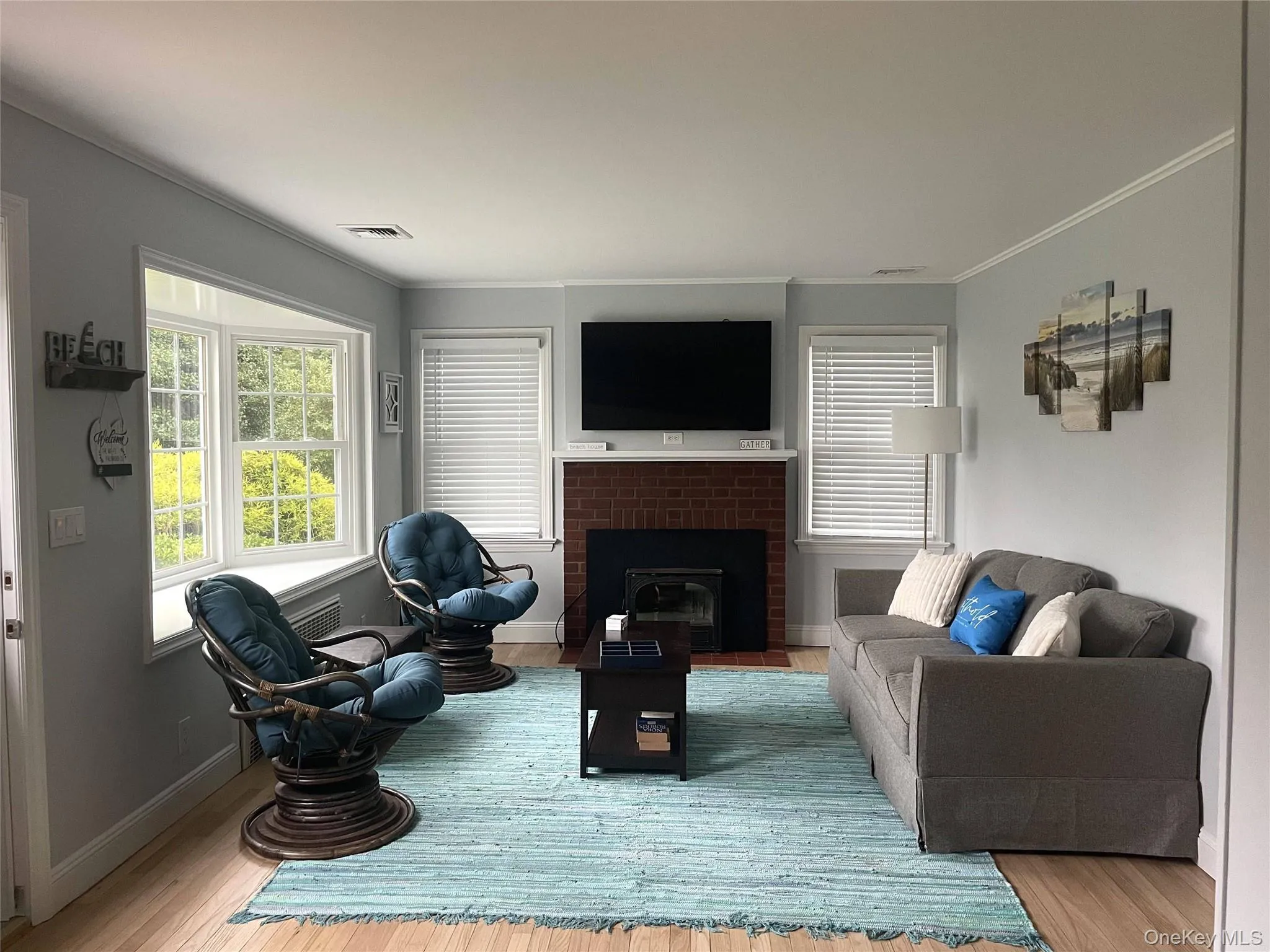 Living room featuring a fireplace, healthy amount of natural light, crown molding, and wood finished floors Living room featuring a fireplace, healthy amount of natural light, crown molding, and wood finished floors