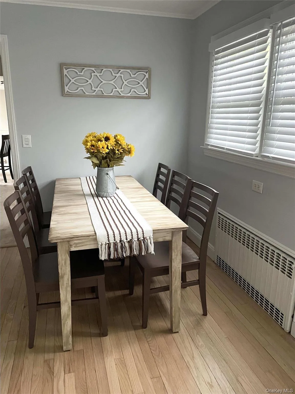 Dining area with radiator, crown molding, and light wood-style flooring Dining area with radiator, crown molding, and light wood-style flooring