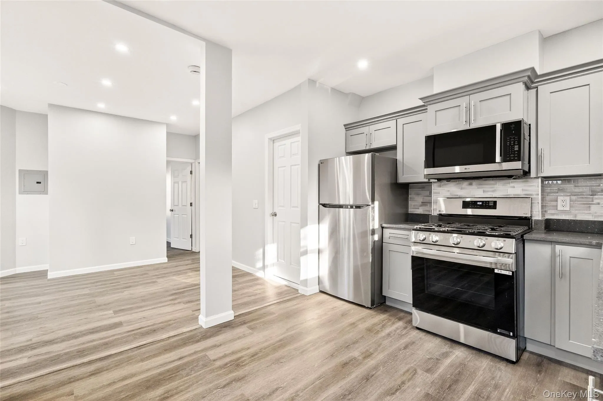 Kitchen with stainless steel appliances, gray cabinets, recessed lighting, backsplash, and light wood-style flooring Kitchen with stainless steel appliances, gray cabinets, recessed lighting, backsplash, and light wood-style flooring