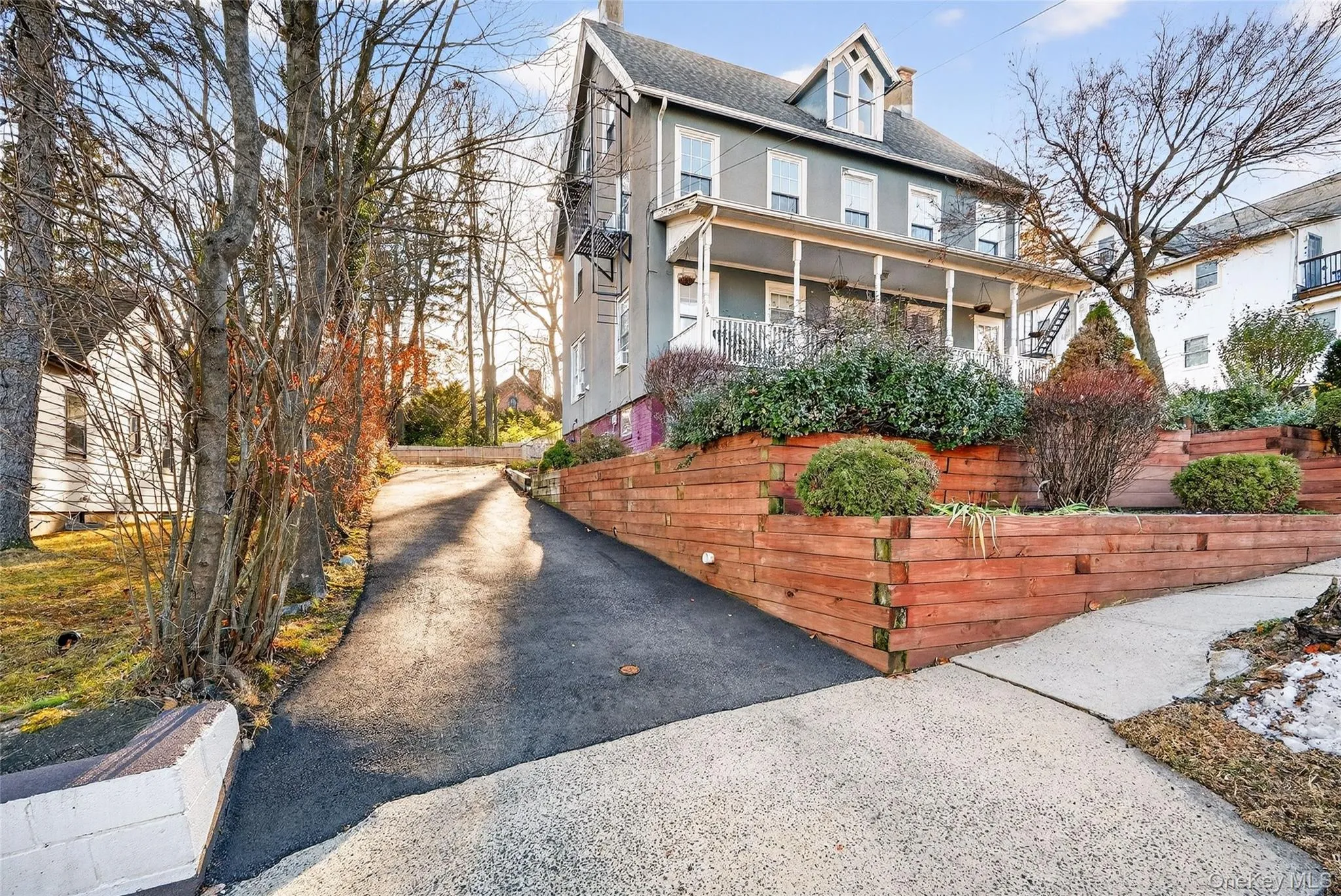 View of front of house with a chimney, a porch, roof with shingles, stucco siding, and asphalt driveway View of front of house with a chimney, a porch, roof with shingles, stucco siding, and asphalt driveway