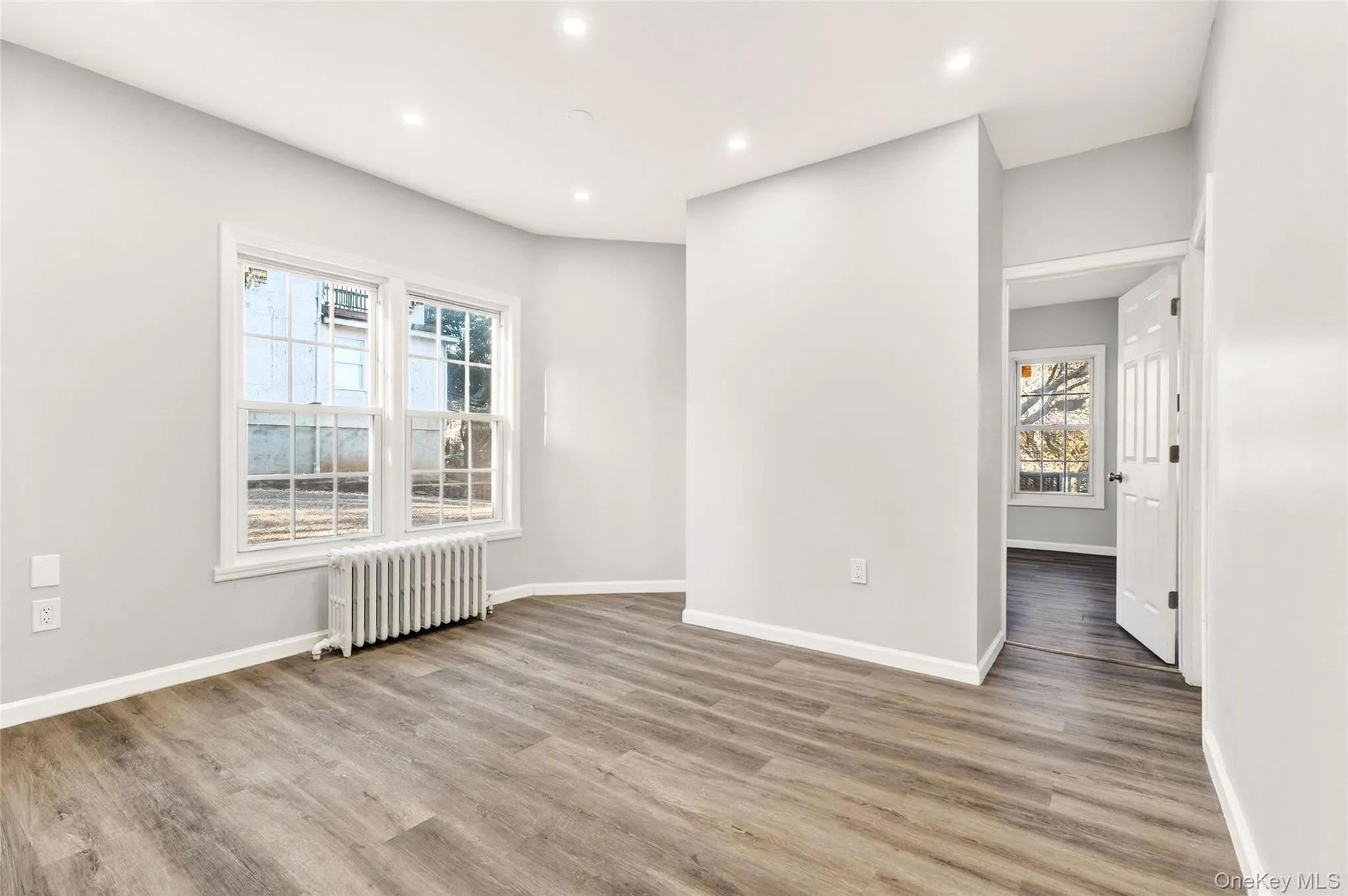 Empty room featuring radiator heating unit, light wood-type flooring, and recessed lighting Empty room featuring radiator heating unit, light wood-type flooring, and recessed lighting