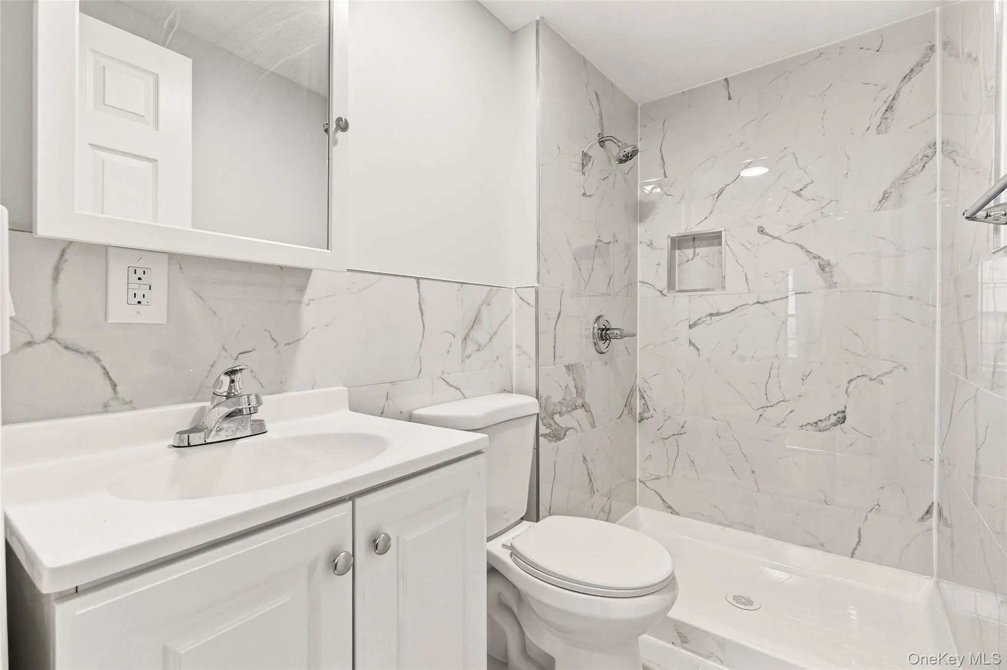 Bathroom featuring vanity, a marble finish shower, and tile walls Bathroom featuring vanity, a marble finish shower, and tile walls