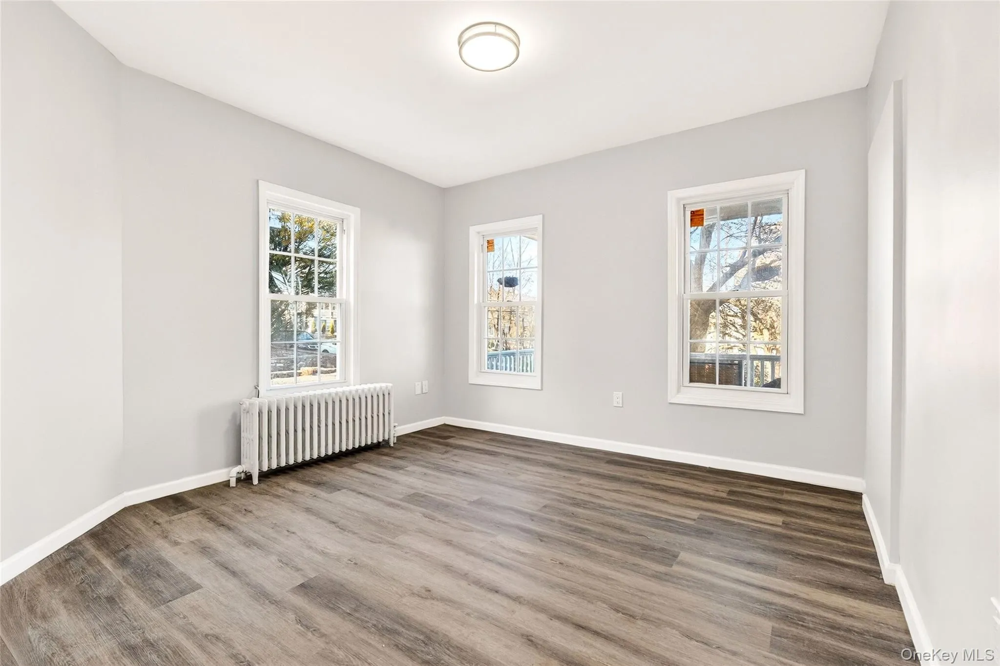 Unfurnished room with radiator and wood finished floors Unfurnished room with radiator and wood finished floors