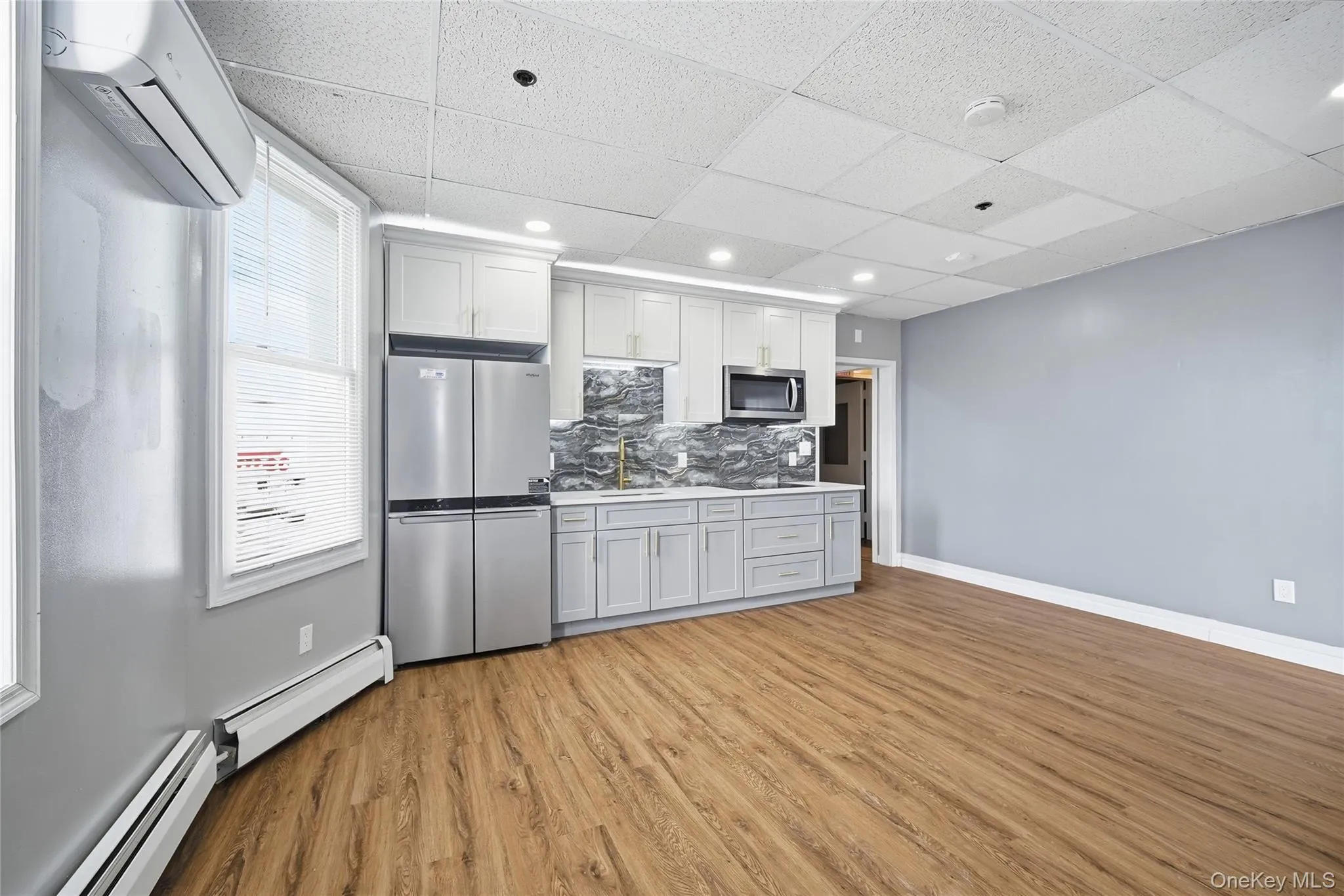 Kitchen with stainless steel appliances, baseboard heating, a wall mounted AC, tasteful backsplash, and recessed lighting Kitchen with stainless steel appliances, baseboard heating, a wall mounted AC, tasteful backsplash, and recessed lighting