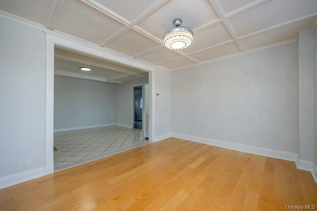 Empty room with coffered ceiling and light wood-style floors Empty room with coffered ceiling and light wood-style floors