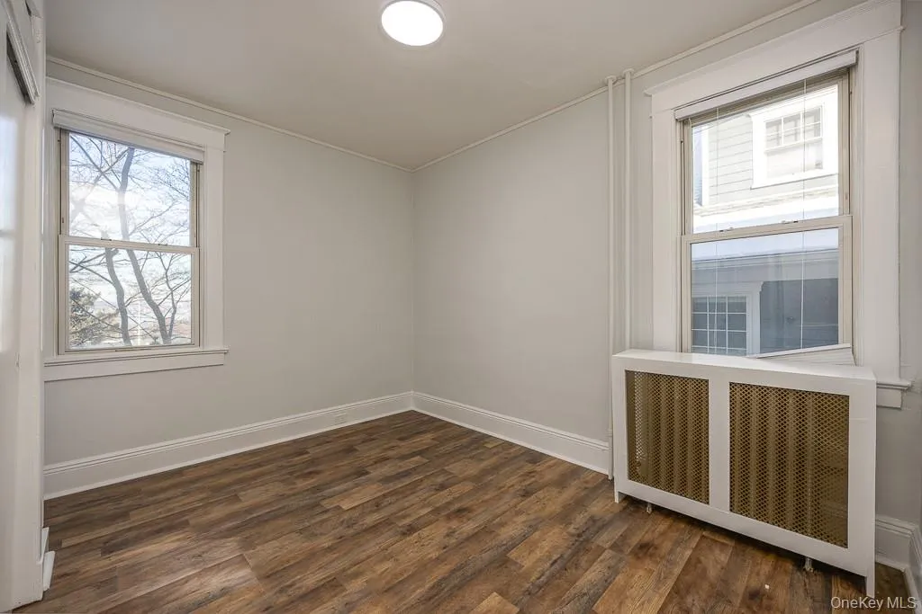 Unfurnished room with radiator and dark wood finished floors Unfurnished room with radiator and dark wood finished floors