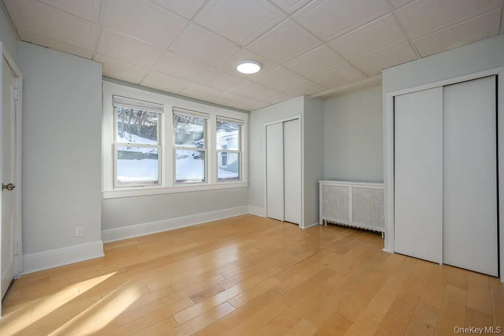 Unfurnished bedroom featuring multiple closets, radiator heating unit, light wood-type flooring, and an ornate ceiling Unfurnished bedroom featuring multiple closets, radiator heating unit, light wood-type flooring, and an ornate ceiling