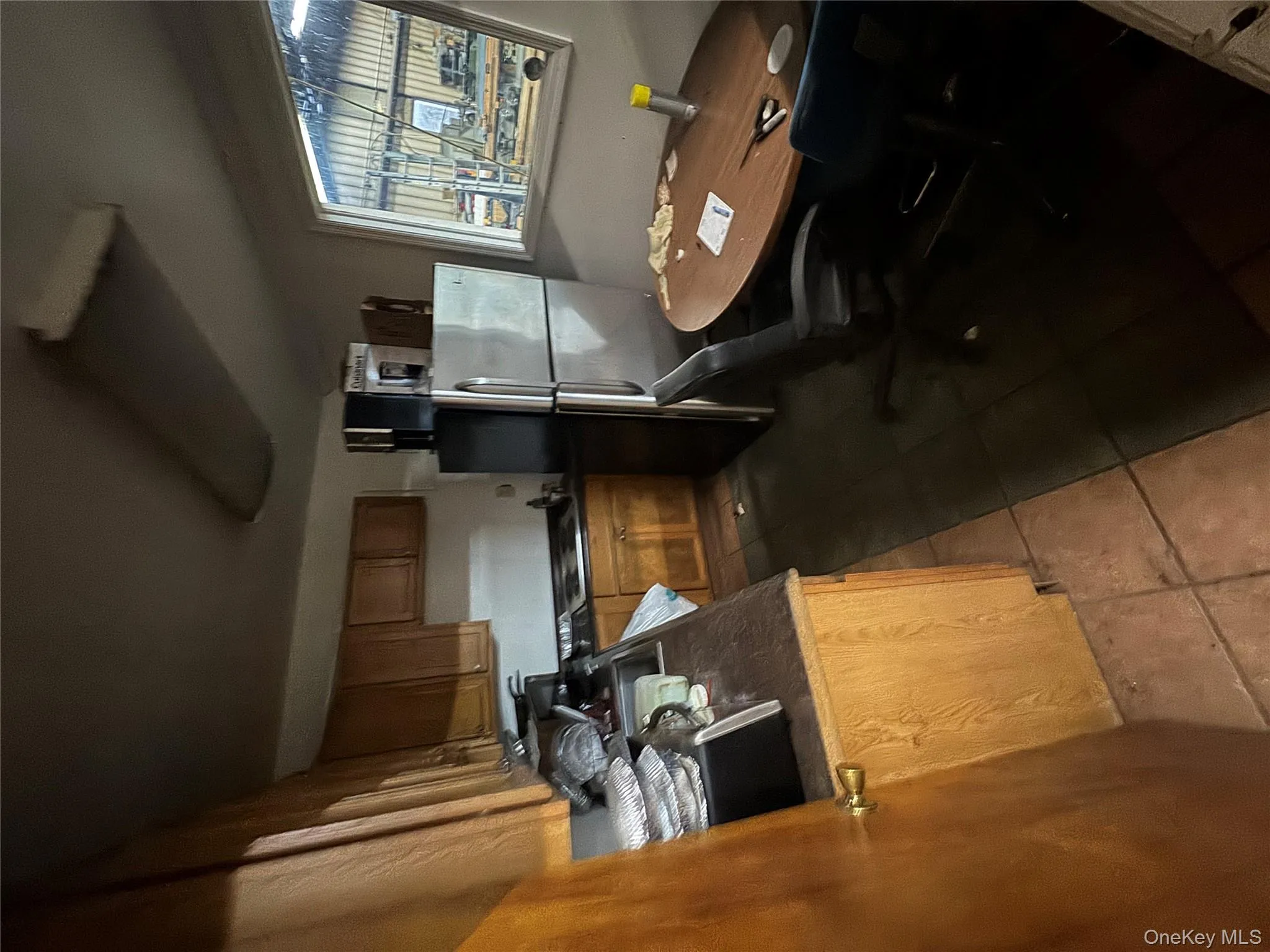 Kitchen with fridge, dark countertops, dark tile patterned flooring, and brown cabinets Kitchen with fridge, dark countertops, dark tile patterned flooring, and brown cabinets