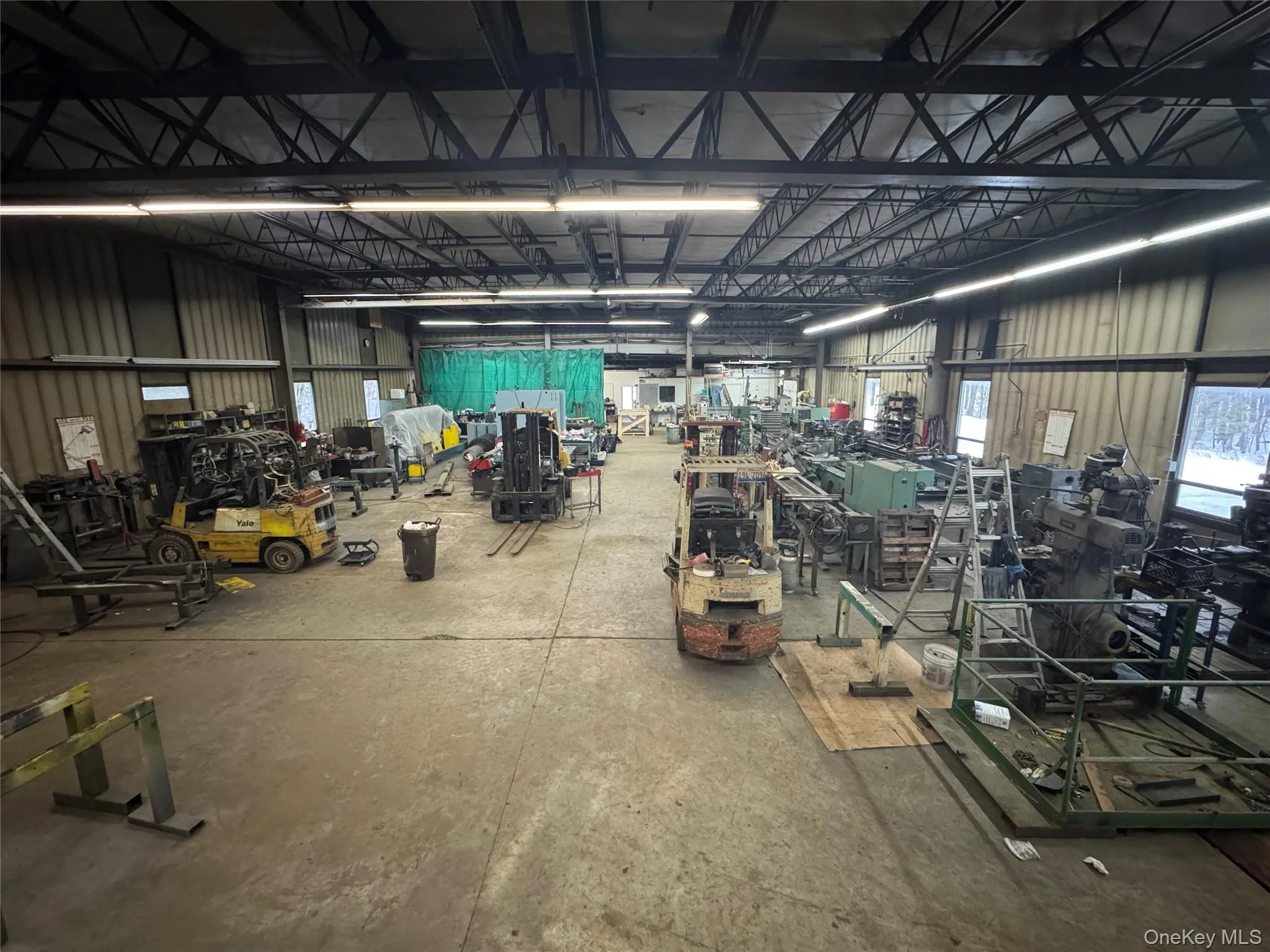 Misc room with metal wall, a workshop area, and a garage Misc room with metal wall, a workshop area, and a garage