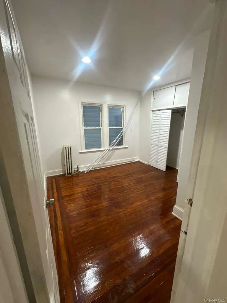 Unfurnished room with dark wood-style flooring, radiator, and recessed lighting Unfurnished room with dark wood-style flooring, radiator, and recessed lighting