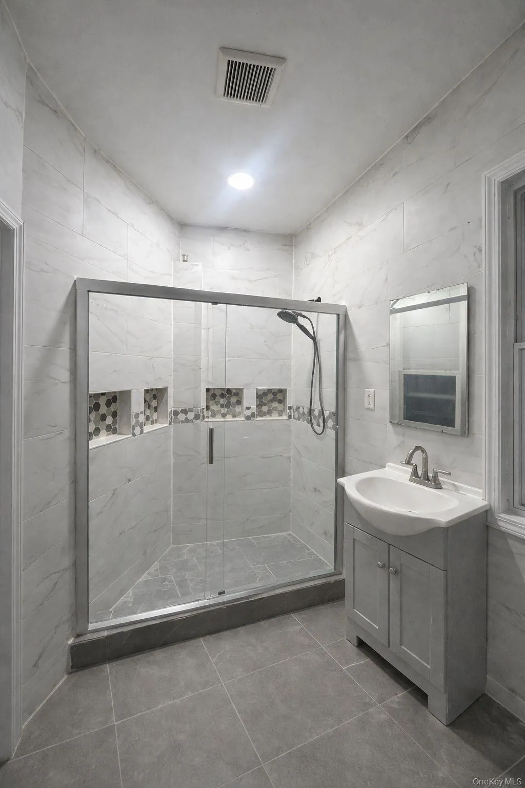 Bathroom with a shower stall, vanity, tile walls, and light tile patterned floors Bathroom with a shower stall, vanity, tile walls, and light tile patterned floors