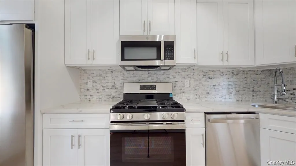 Kitchen with appliances with stainless steel finishes, white cabinets, and light stone countertops Kitchen with appliances with stainless steel finishes, white cabinets, and light stone countertops