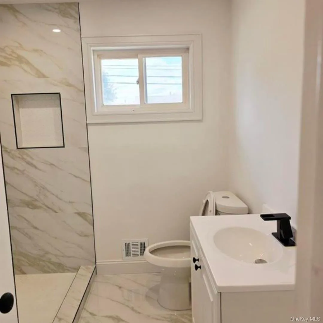 Bathroom featuring light marble finish floors, vanity, and a marble finish shower Bathroom featuring light marble finish floors, vanity, and a marble finish shower