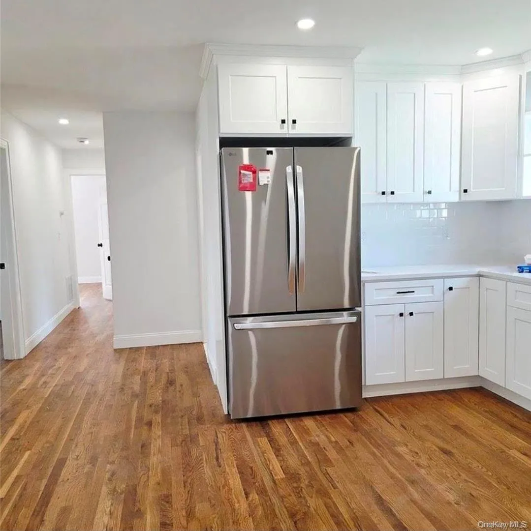 Kitchen with white cabinetry, freestanding refrigerator, decorative backsplash, light wood-type flooring, and recessed lighting Kitchen with white cabinetry, freestanding refrigerator, decorative backsplash, light wood-type flooring, and recessed lighting