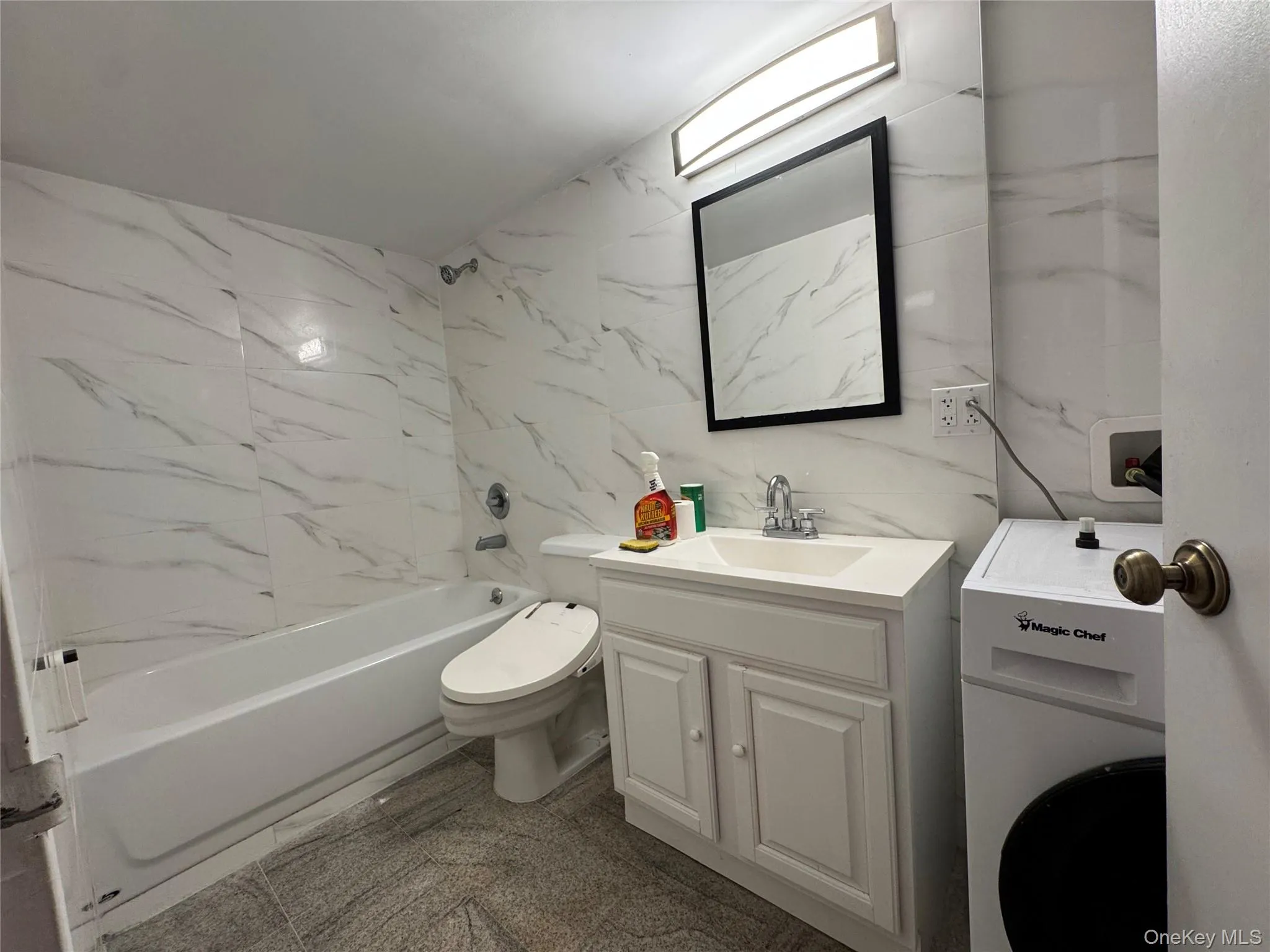 Bathroom featuring tile walls, washer / clothes dryer, vanity, and tub / shower combination Bathroom featuring tile walls, washer / clothes dryer, vanity, and tub / shower combination