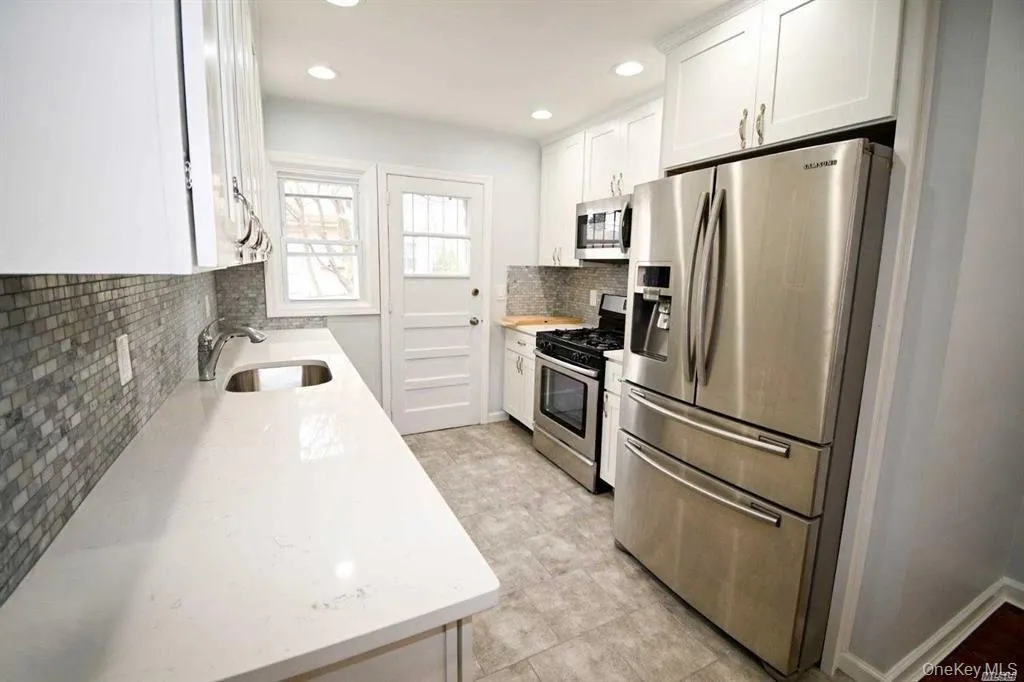 Kitchen with appliances with stainless steel finishes, white cabinetry, light stone countertops, recessed lighting, and decorative backsplash Kitchen with appliances with stainless steel finishes, white cabinetry, light stone countertops, recessed lighting, and decorative backsplash