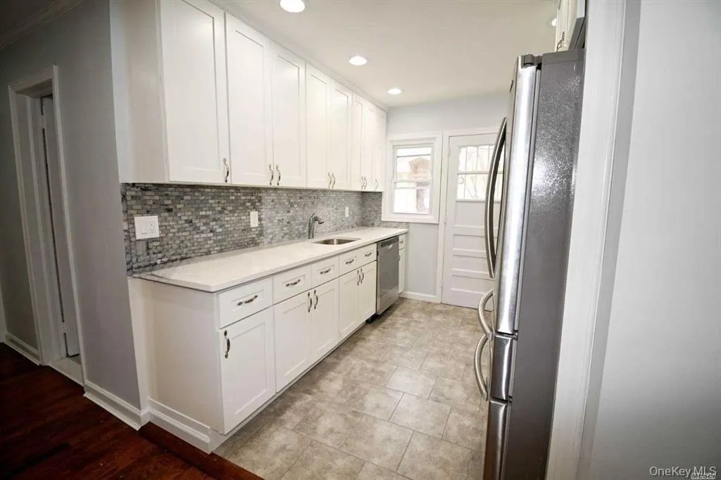 Kitchen featuring appliances with stainless steel finishes, white cabinetry, recessed lighting, tasteful backsplash, and light stone countertops Kitchen featuring appliances with stainless steel finishes, white cabinetry, recessed lighting, tasteful backsplash, and light stone countertops